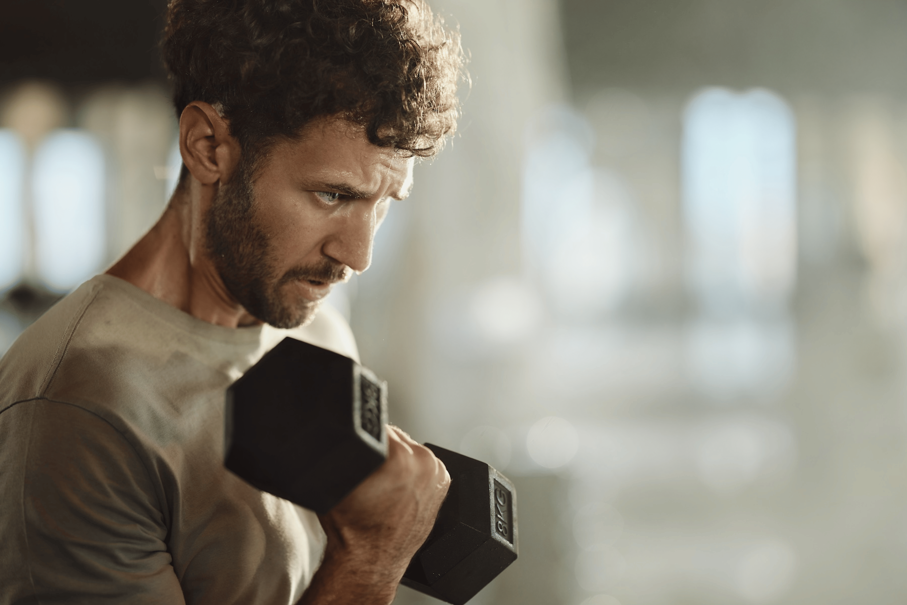 A man lifting a dumbbell. He is locked in to his workout.