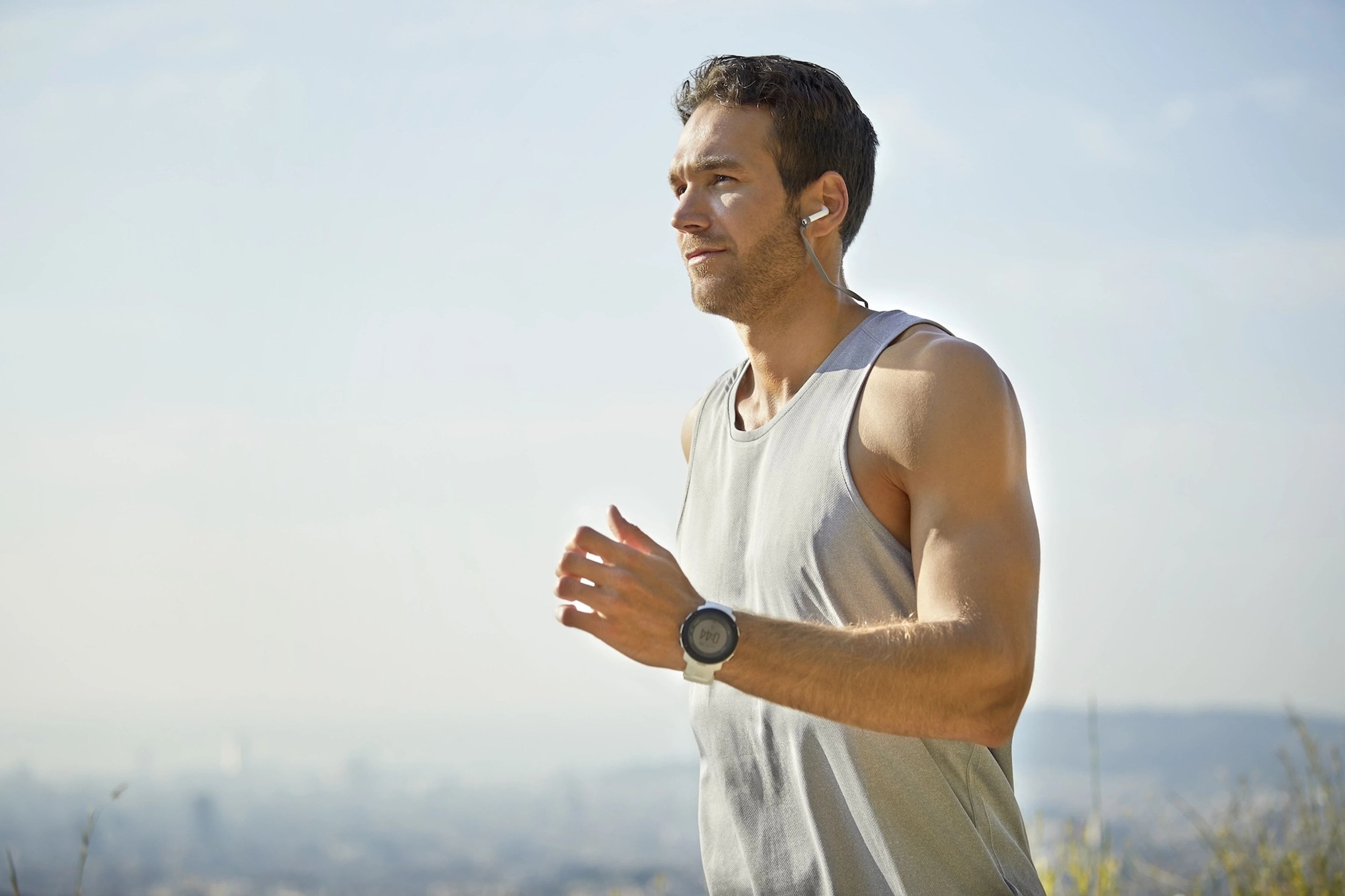 A man meeting his new goal of running by going for a run on a sunny day.