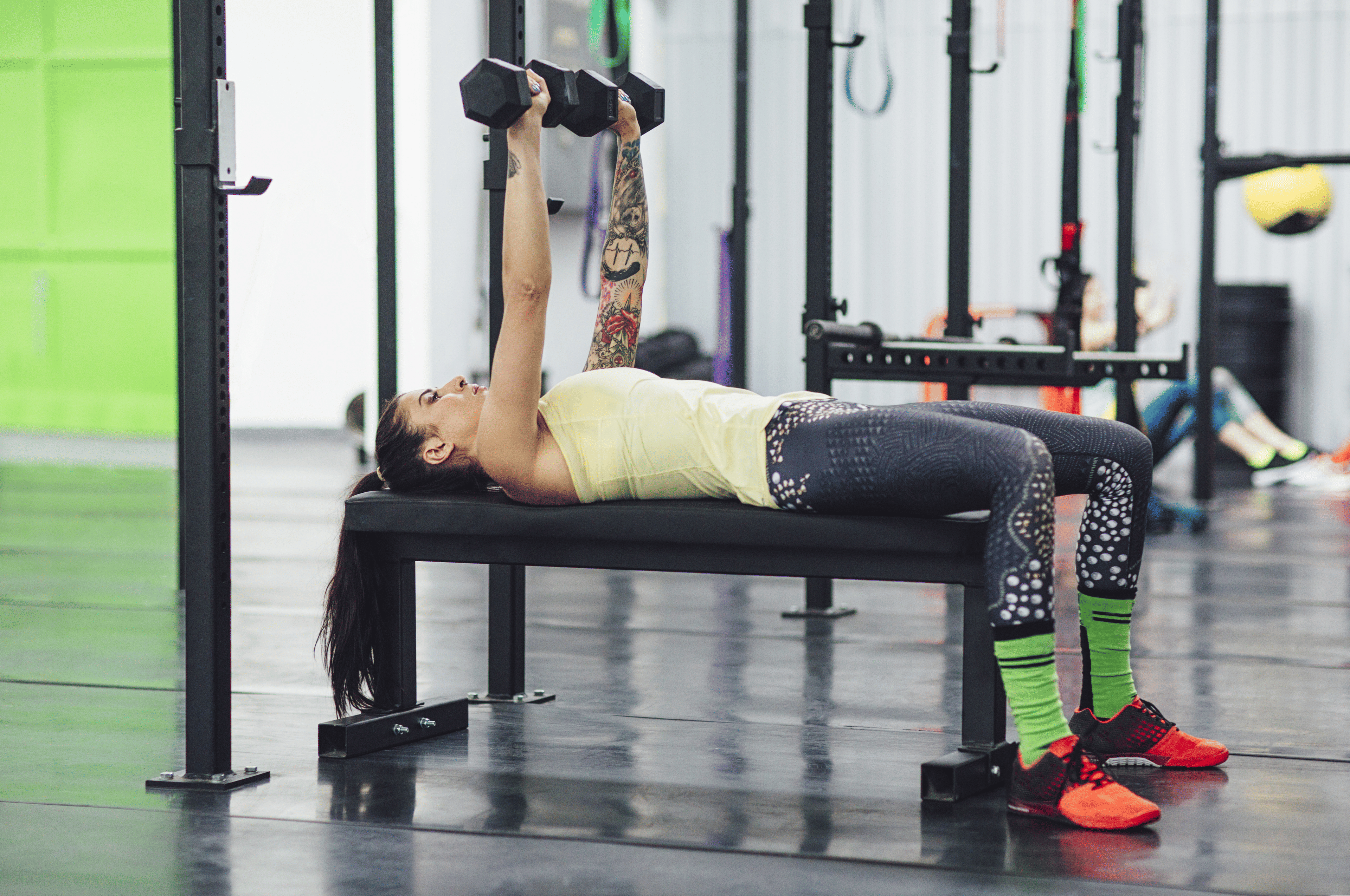 Woman does a dumbbell bench press exercise at gym 