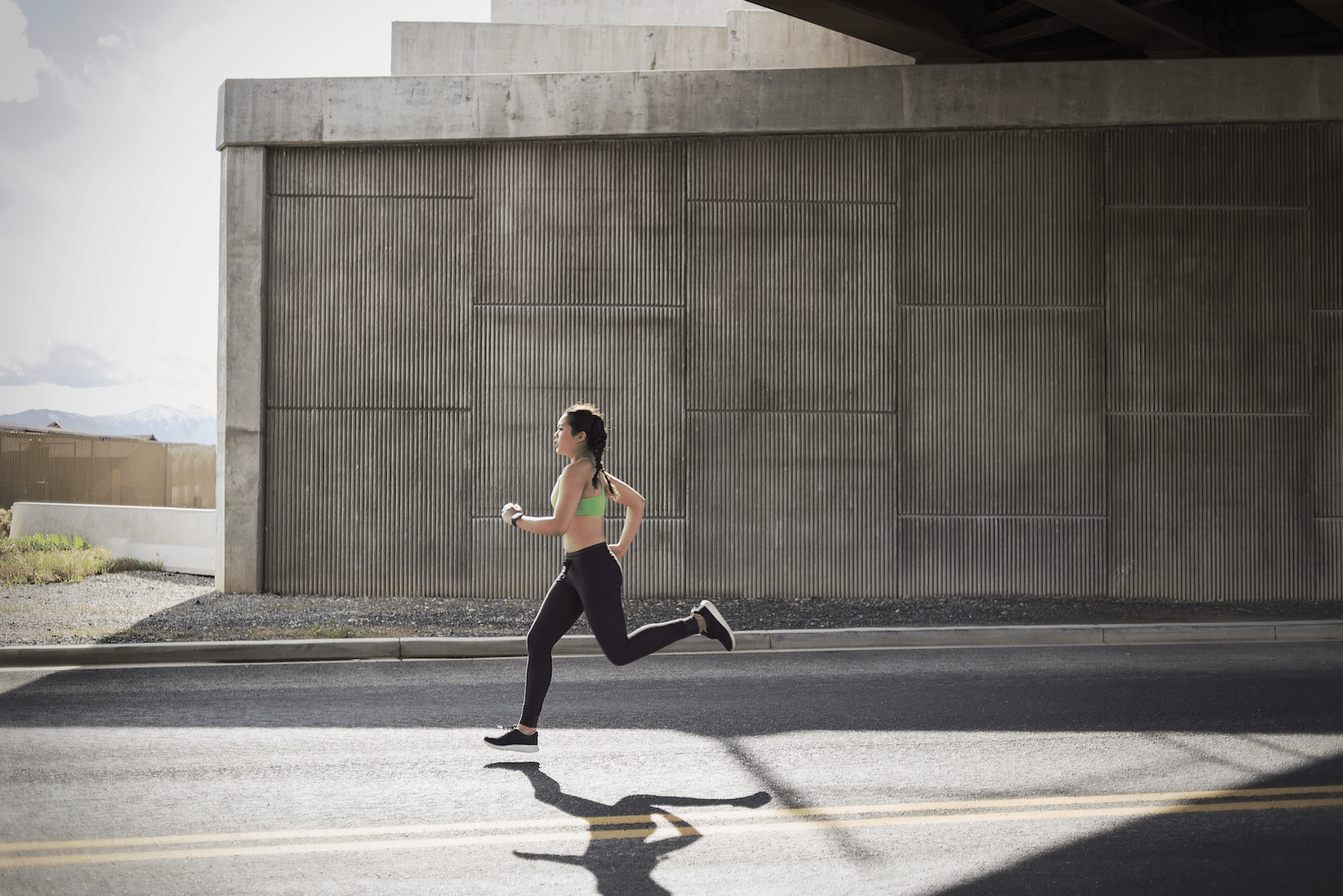 A young athlete going on a run under a freeway overpass.