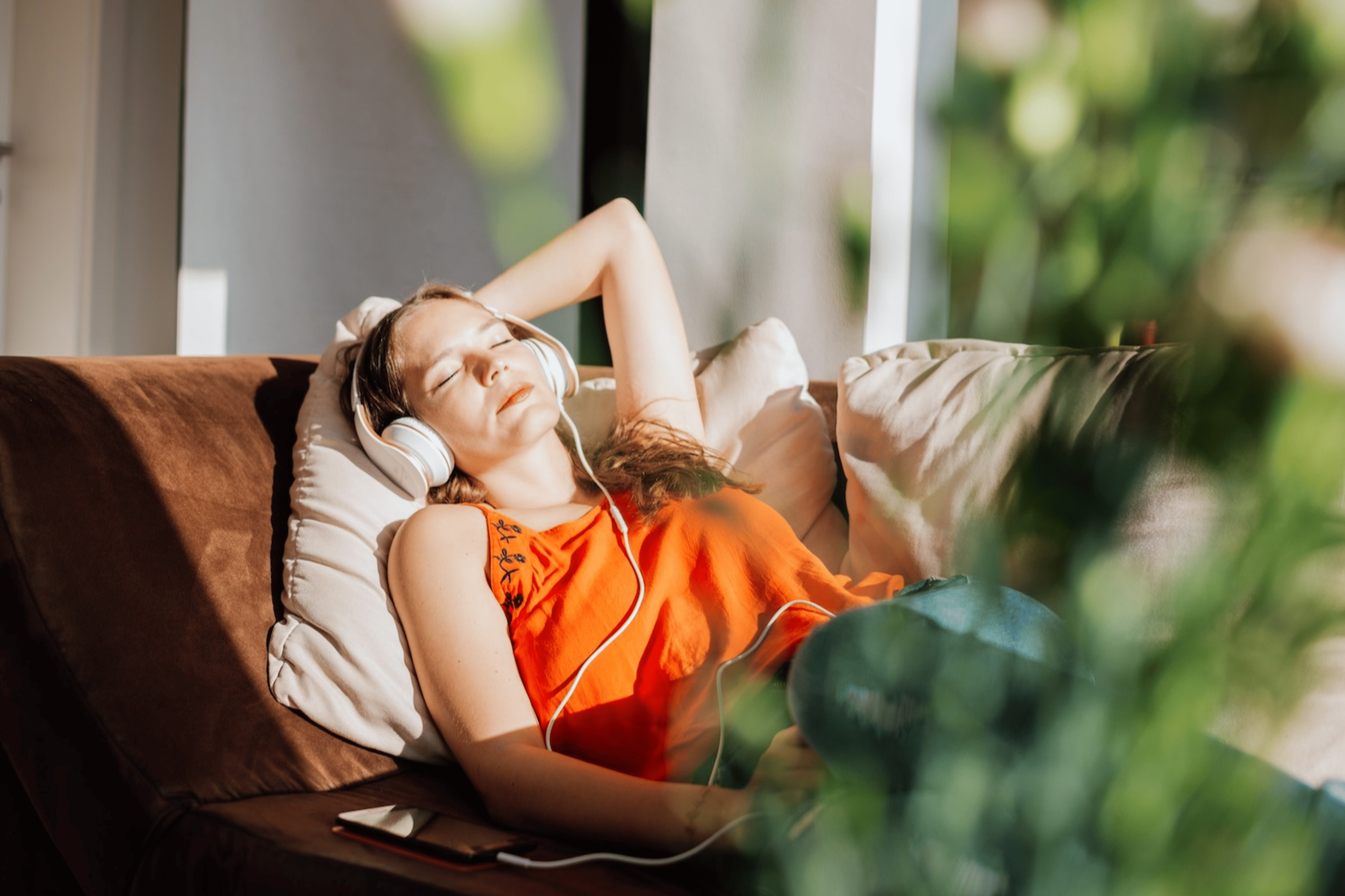 A woman resting in the sunlight at home while listening to music.