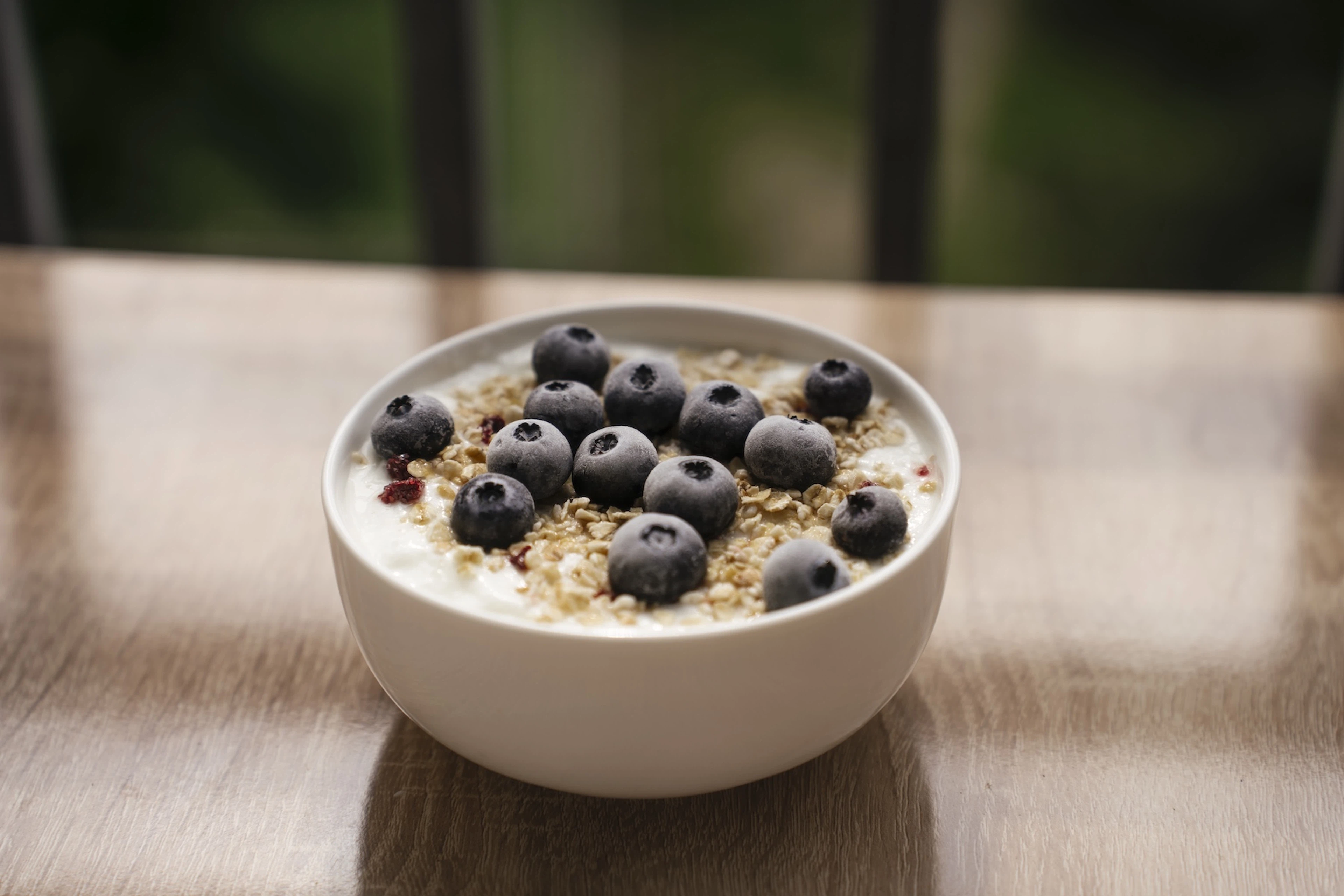 A close-up photo of a bowl with yogurt, granola, and blueberries. Blueberries are an antioxidant-rich food.