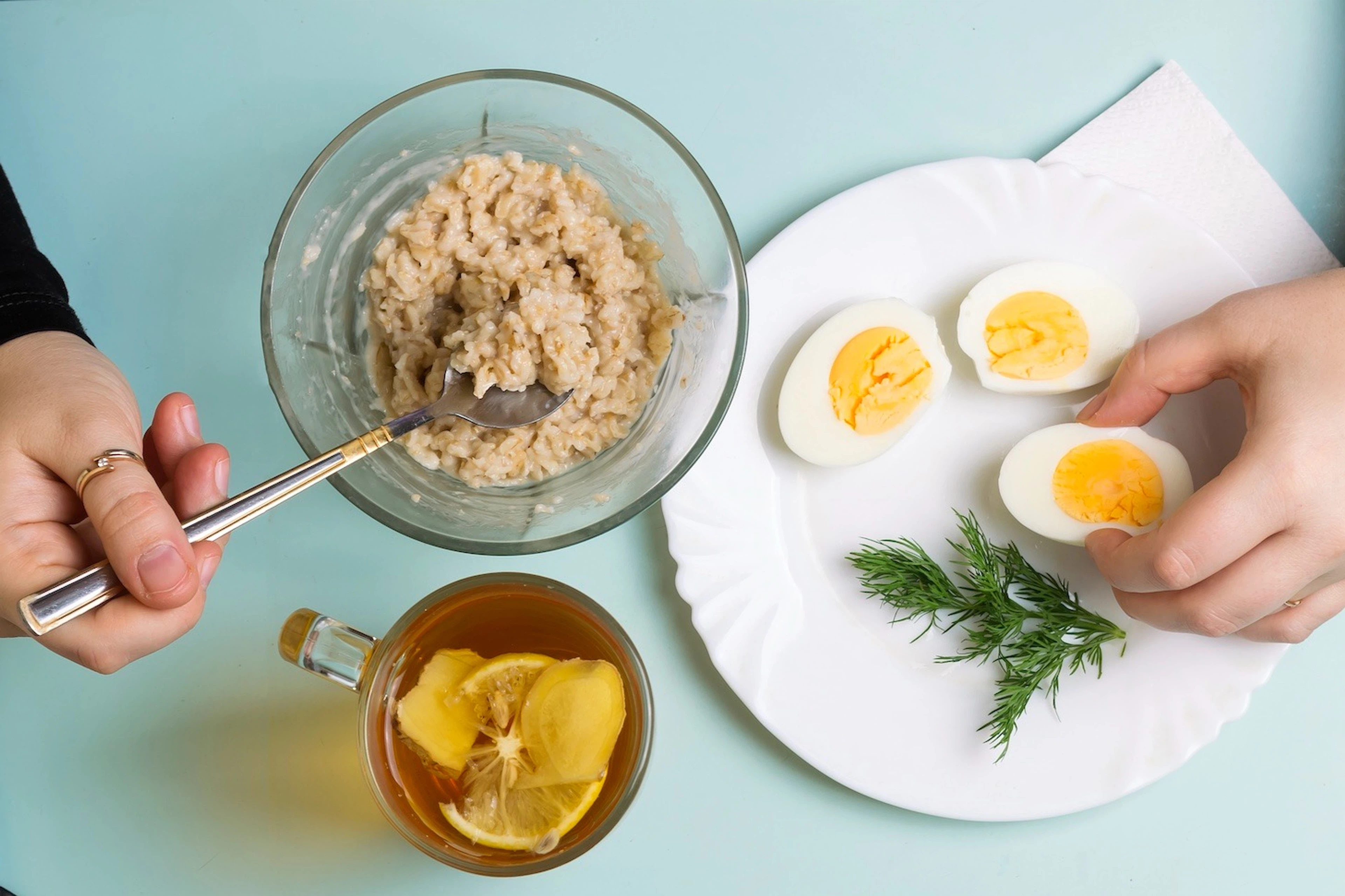 A close-up photo of a person eating oatmeal and hard-boiled eggs.