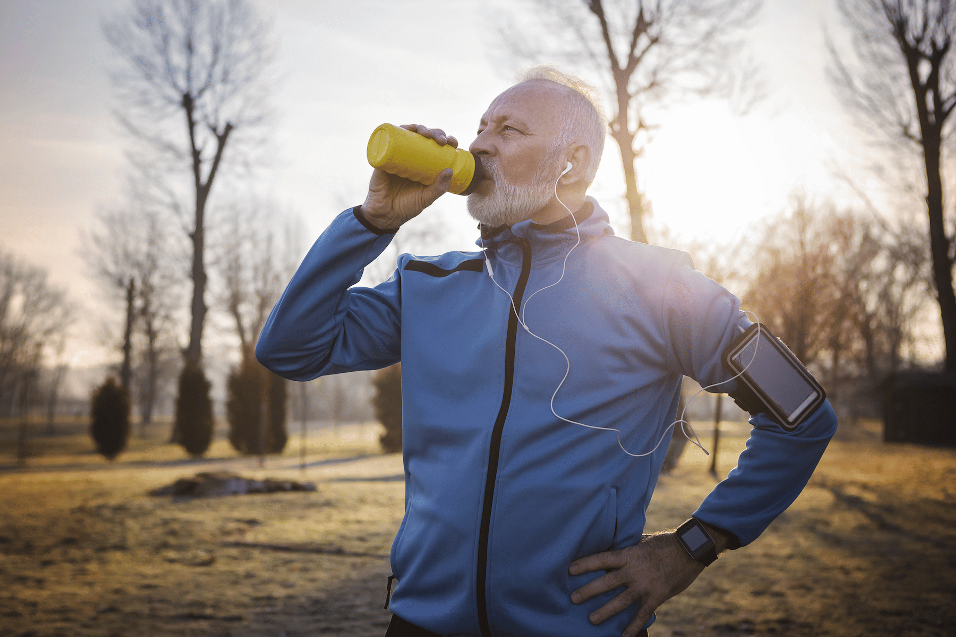 Man drinks from his water bottle while running