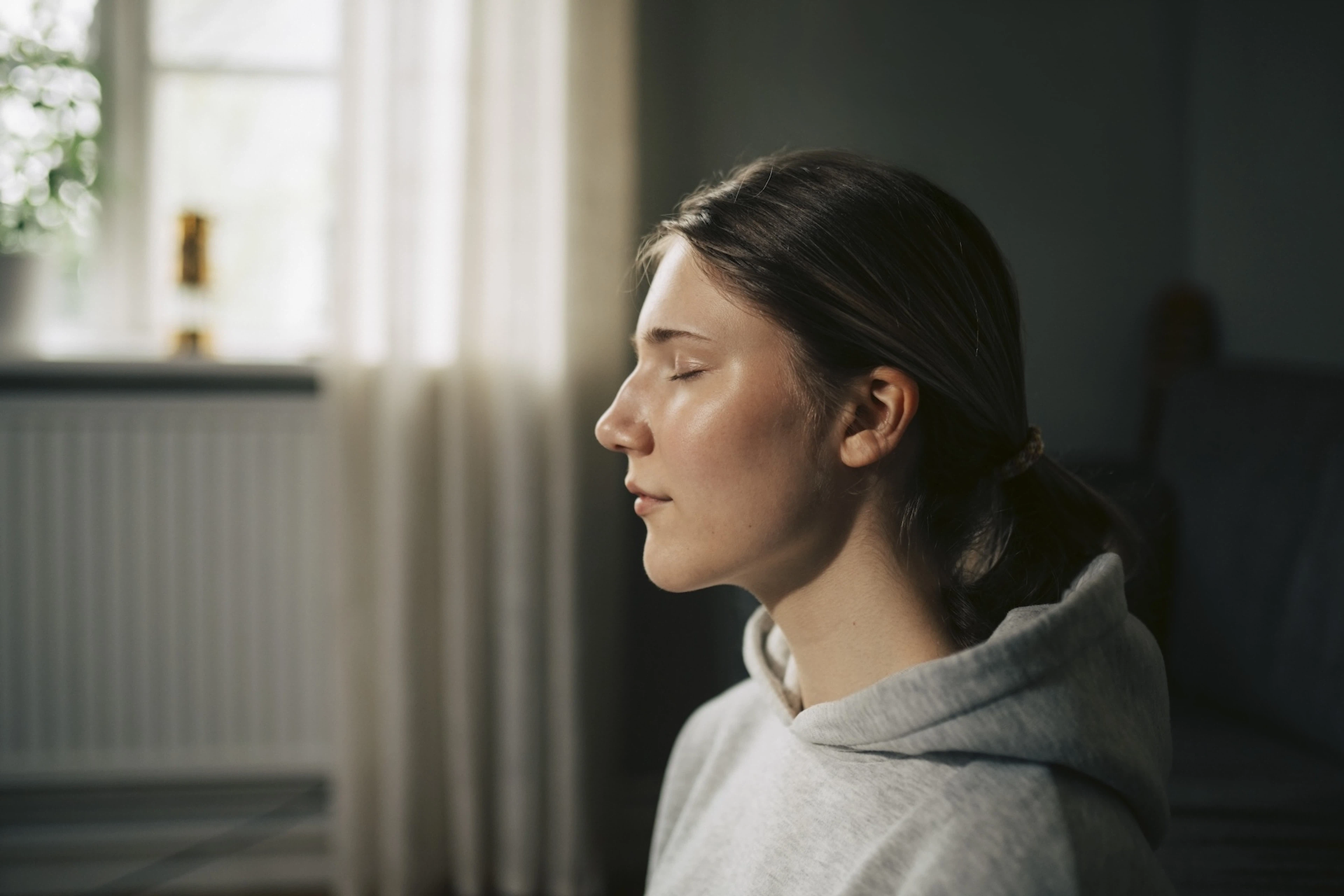 A side-profile view of a woman meditating with her eyes closed.
