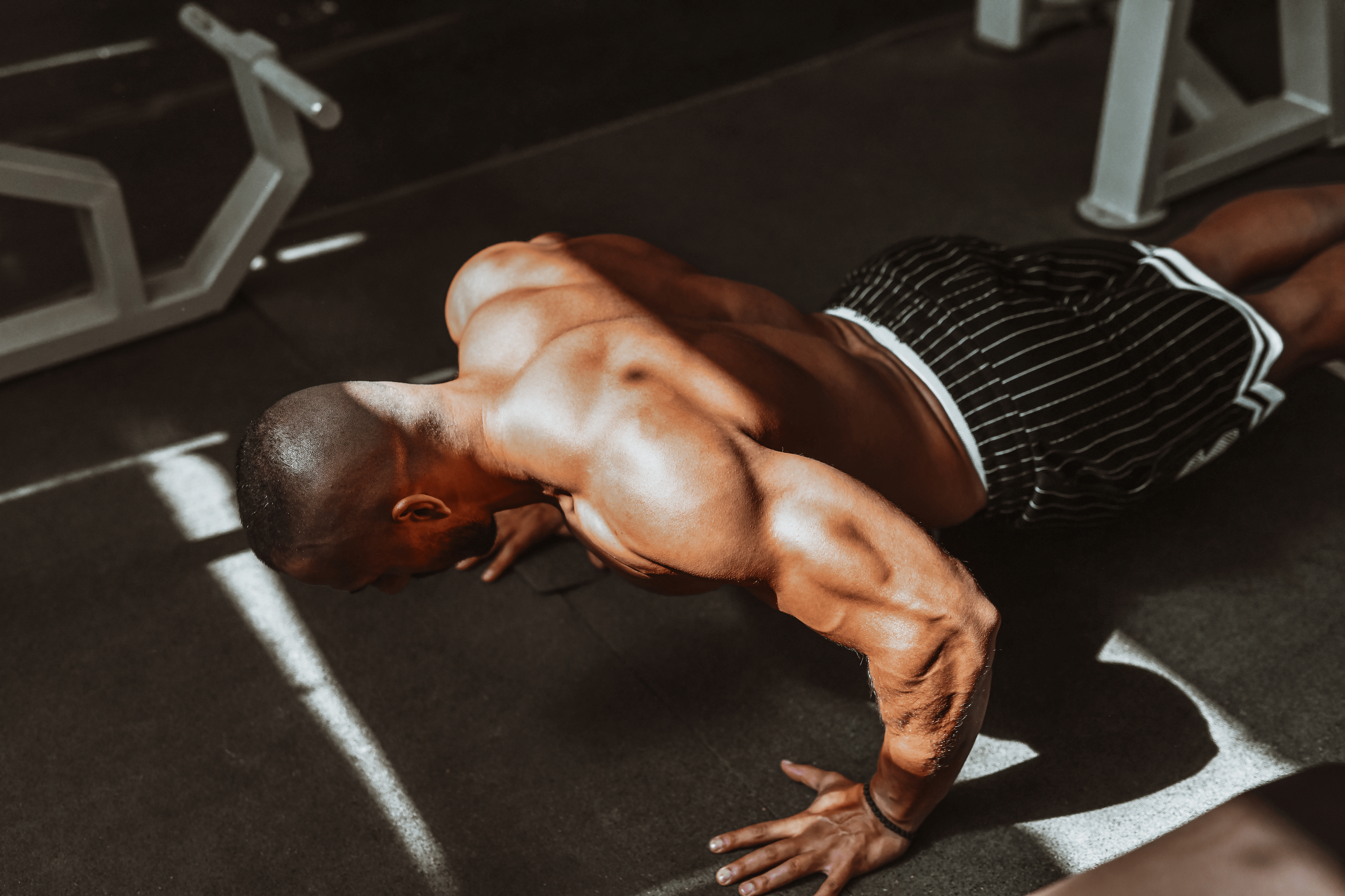 Man doing bodyweight back exercises in a gym.