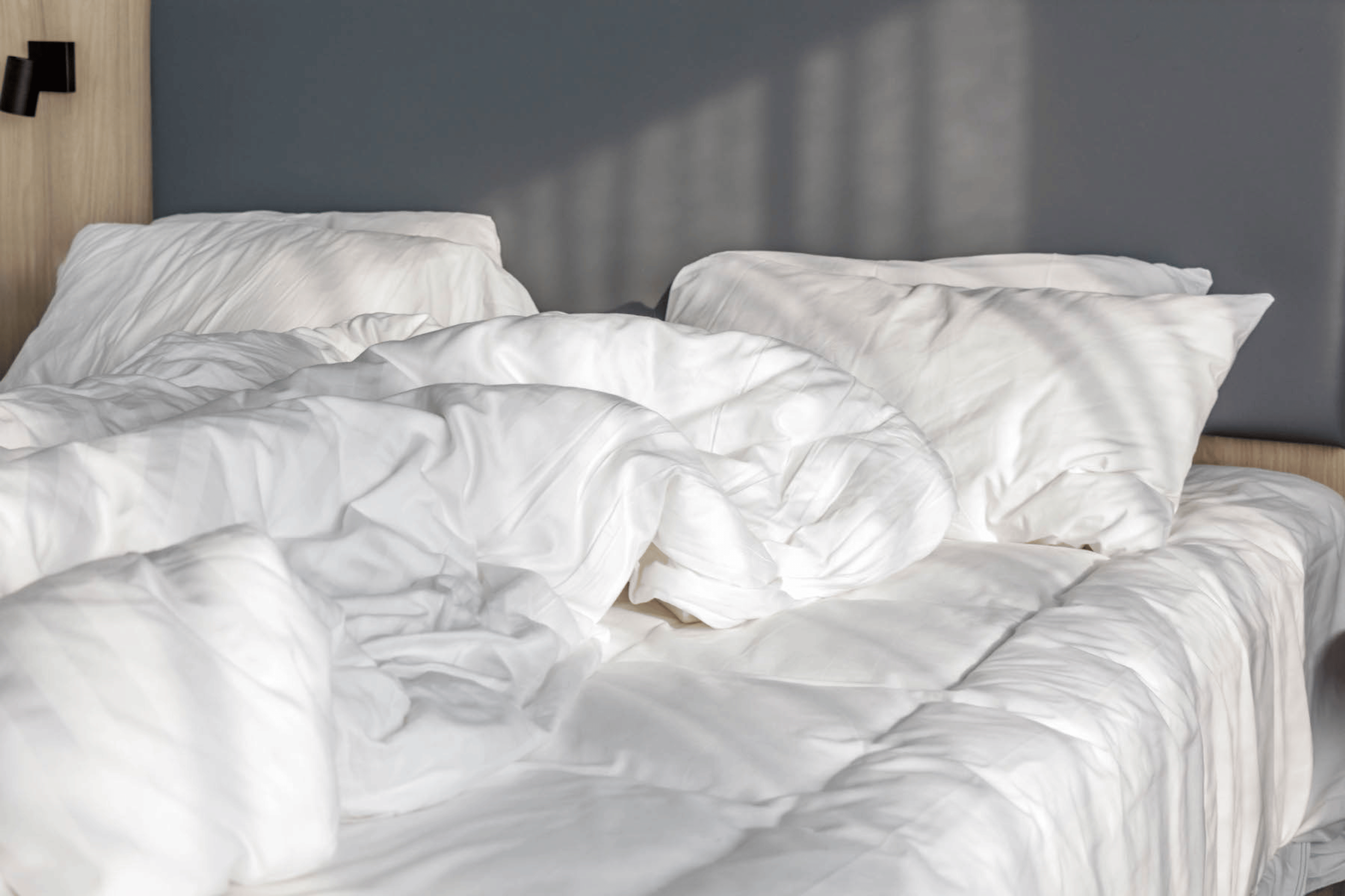 Scandinavian sleep method: Messy white blankets on a bed.