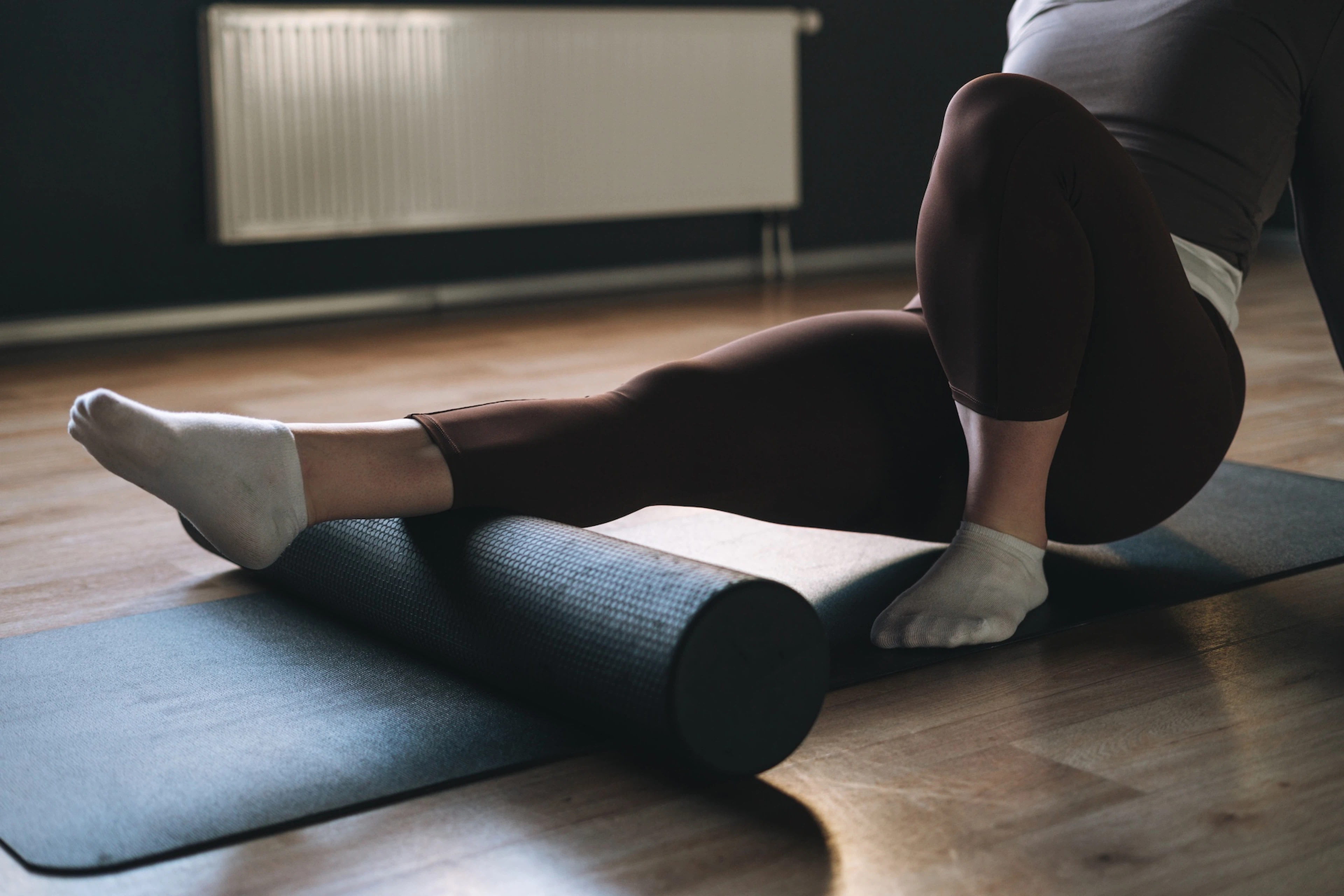 A woman foam rolling her right calf before a workout.