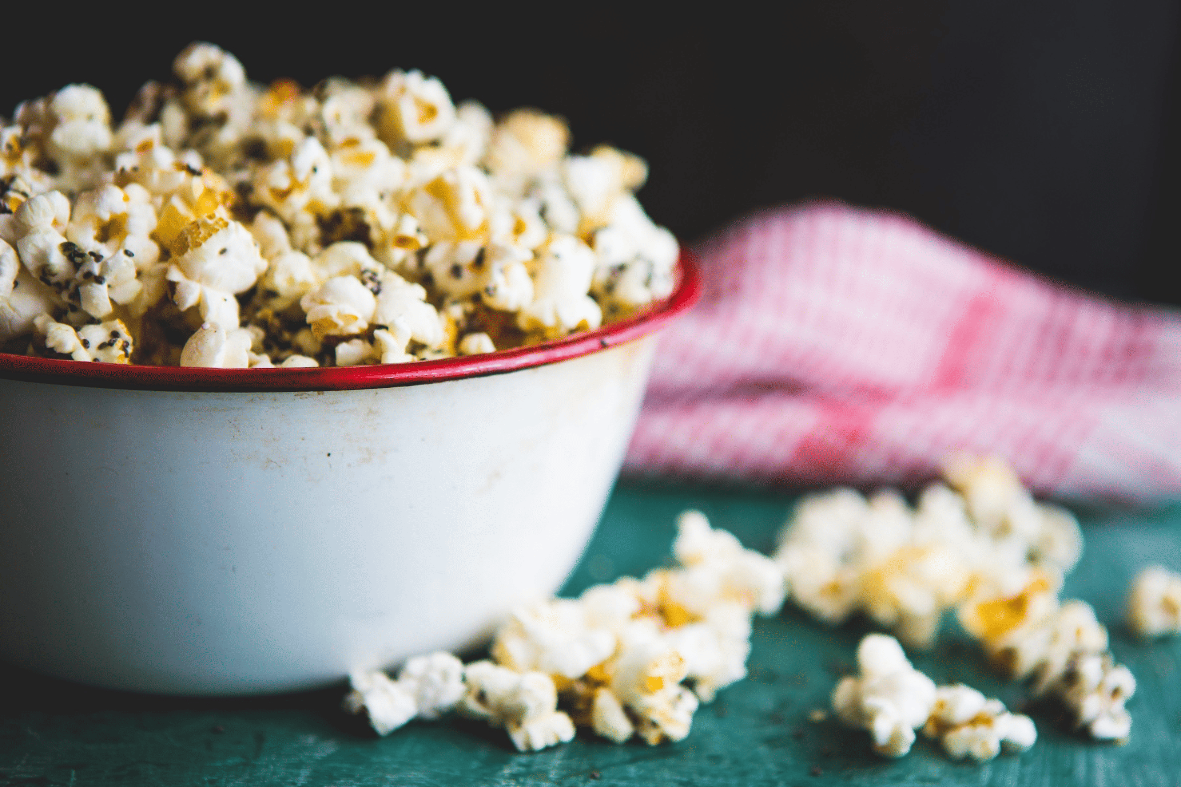 A bowl of popcorn with nutritional yeast and other spices and grains. Adding nutritional yeast to popcorn is an easy way to add more protein to your diet.