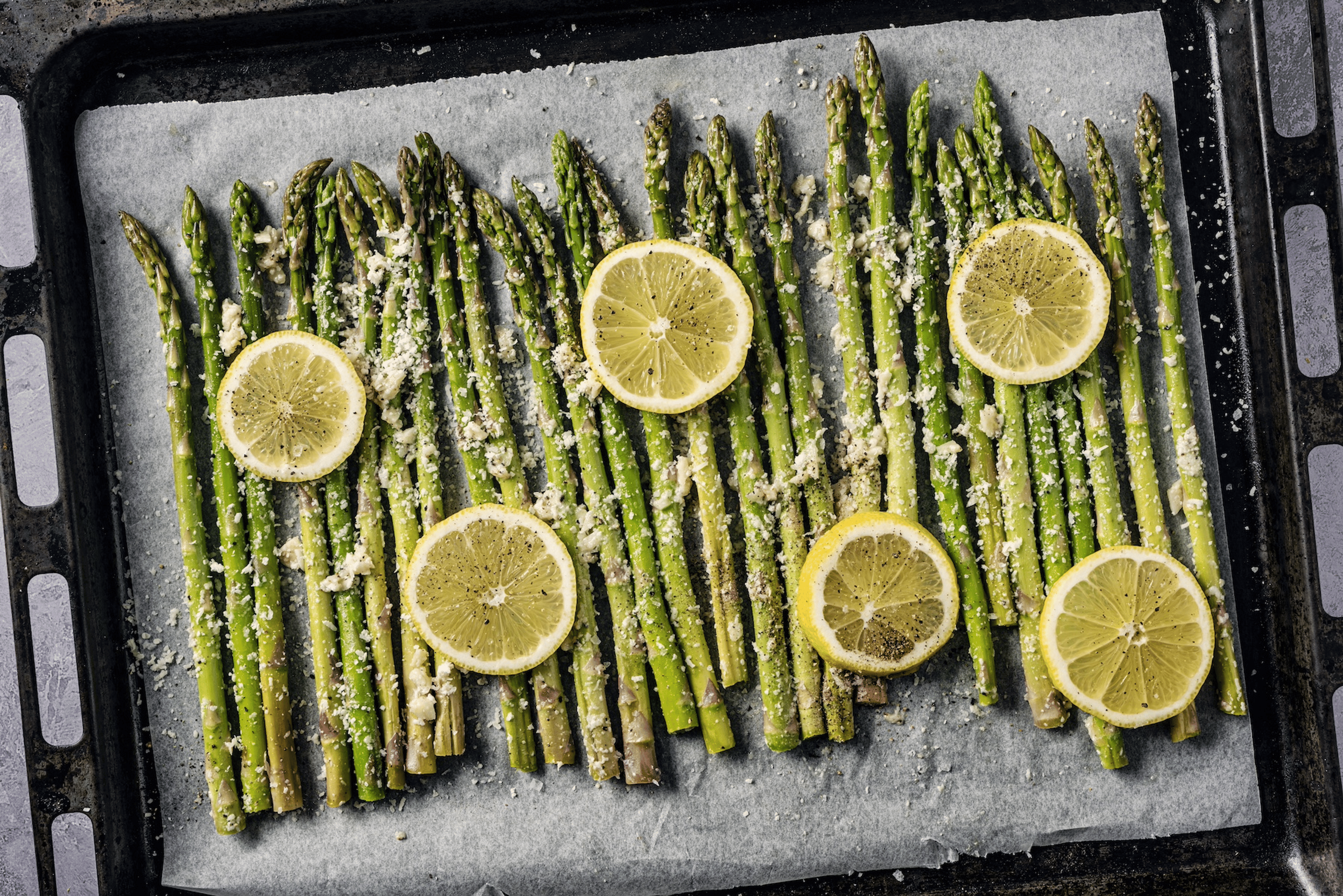 Lemon-roasted asparagus on a sheet pan with parmesan sprinkled on top. Asparagus is a high-protein vegetable.