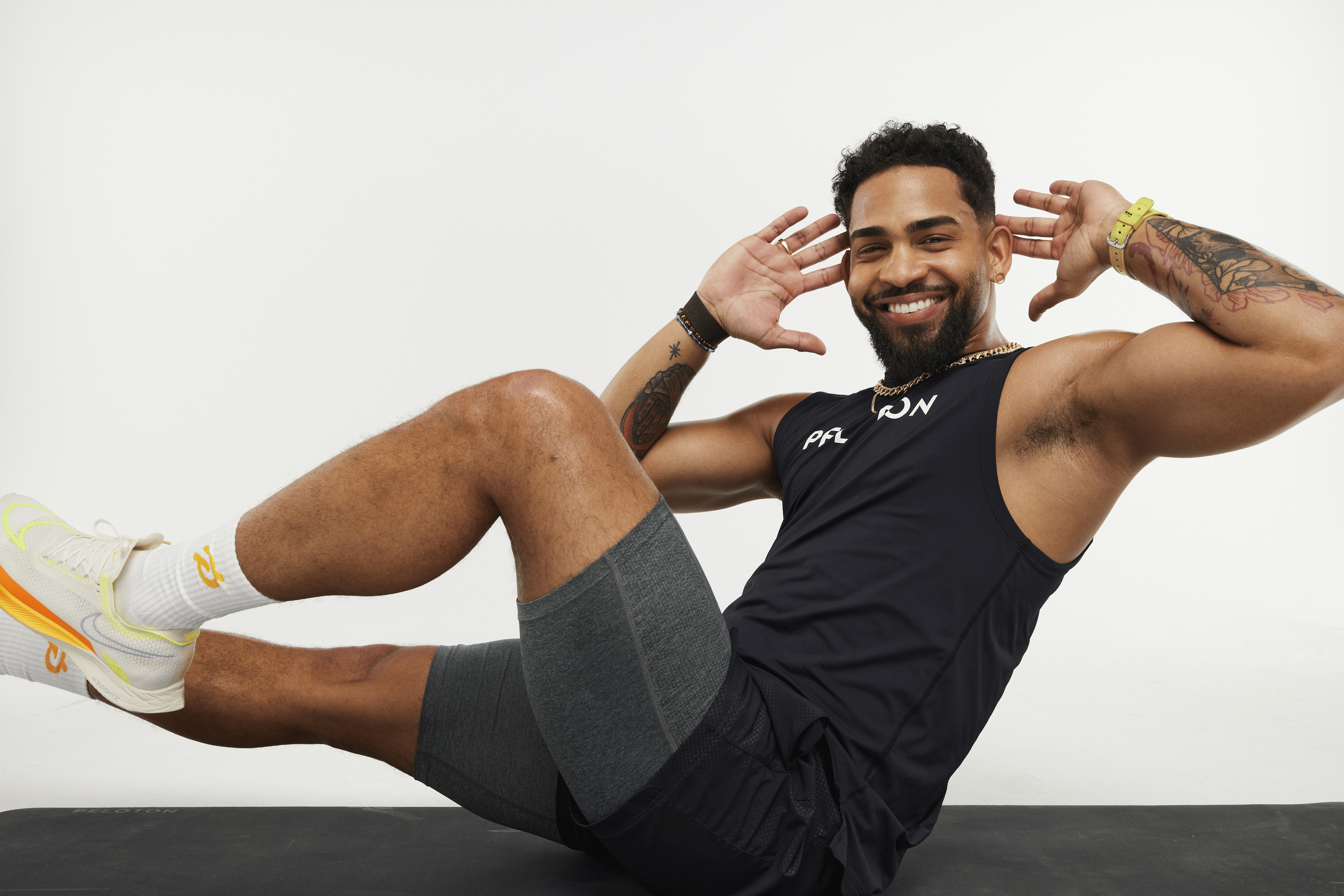 Peloton instructor Rad Lopez doing bicycle crunches on a white background