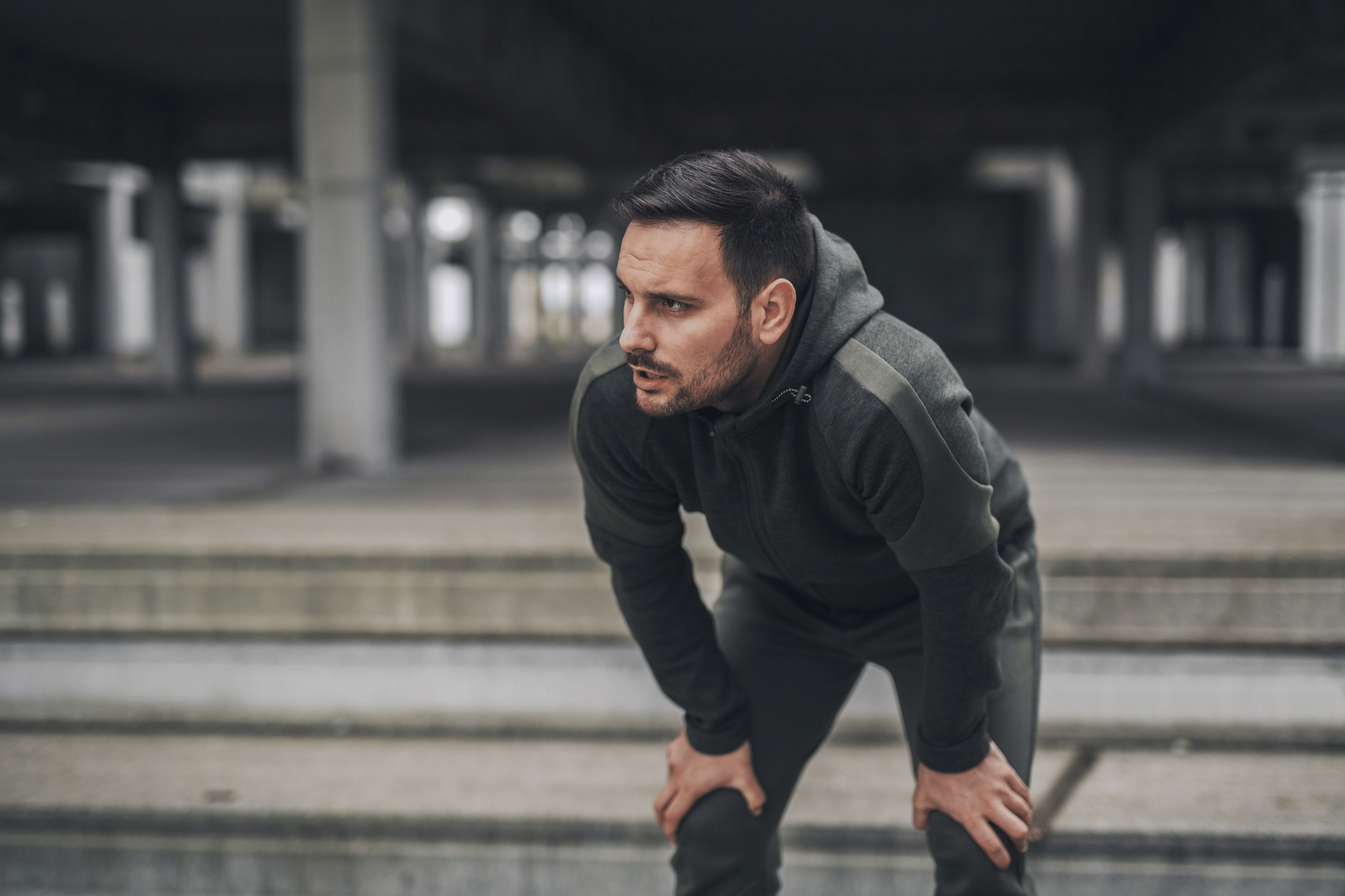 A man catching his breath after a run, with his hands on his knees. He is not hungry after his workout.