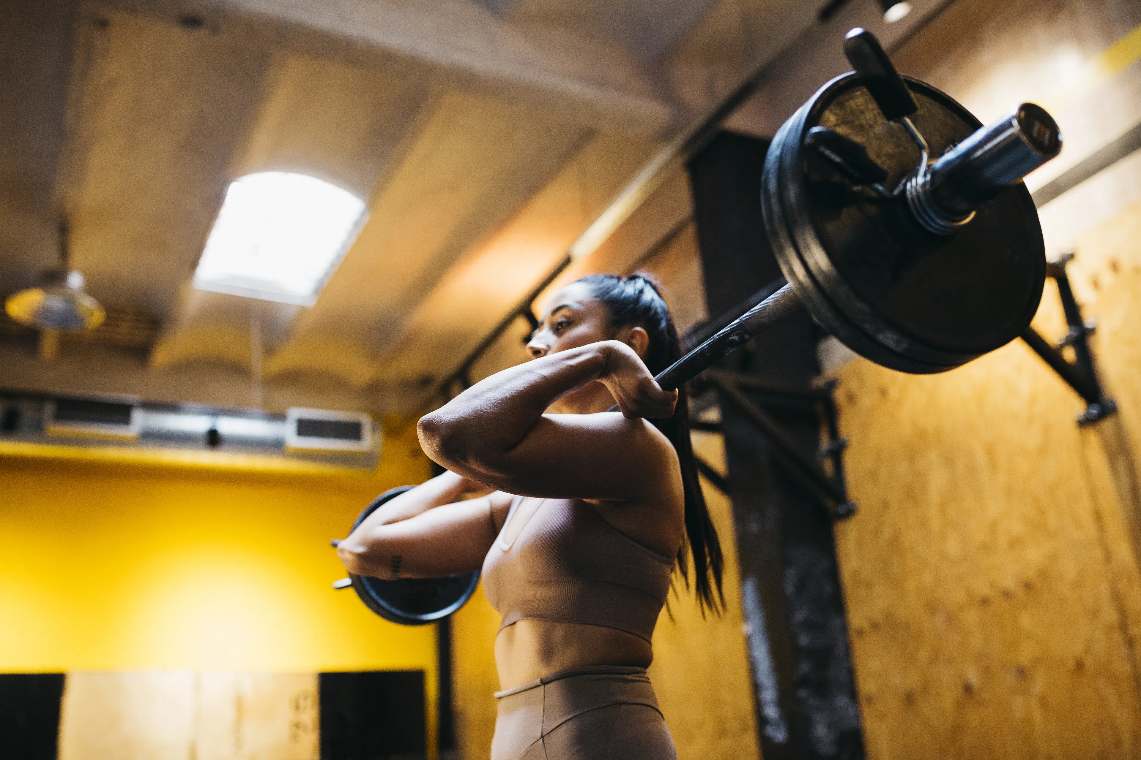 Woman lifting a loaded barbell in a gym doing a strength training program for increasing training volume.