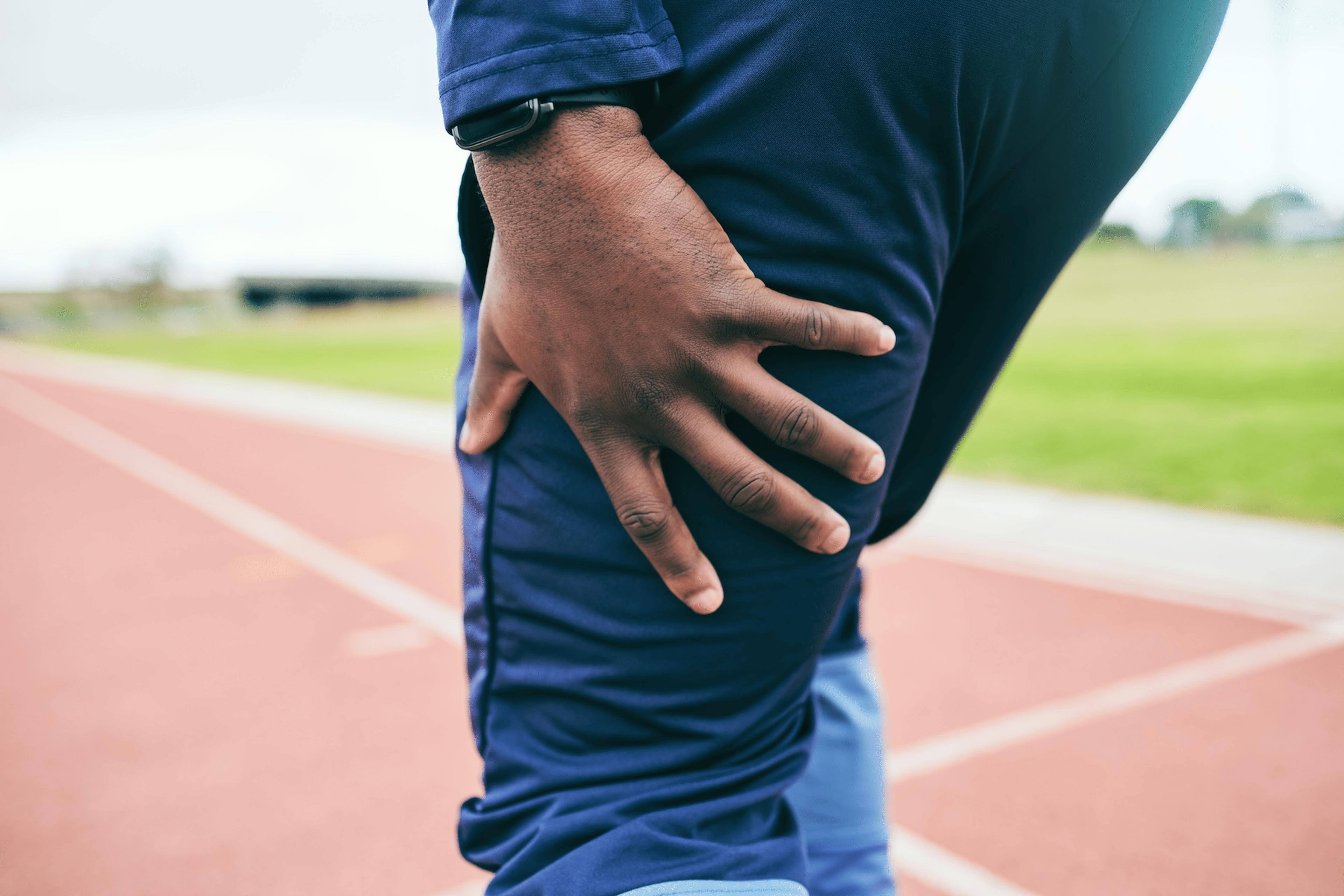 A close-up photo of a man holding his thigh as he experiences a muscle twitch after a workout.