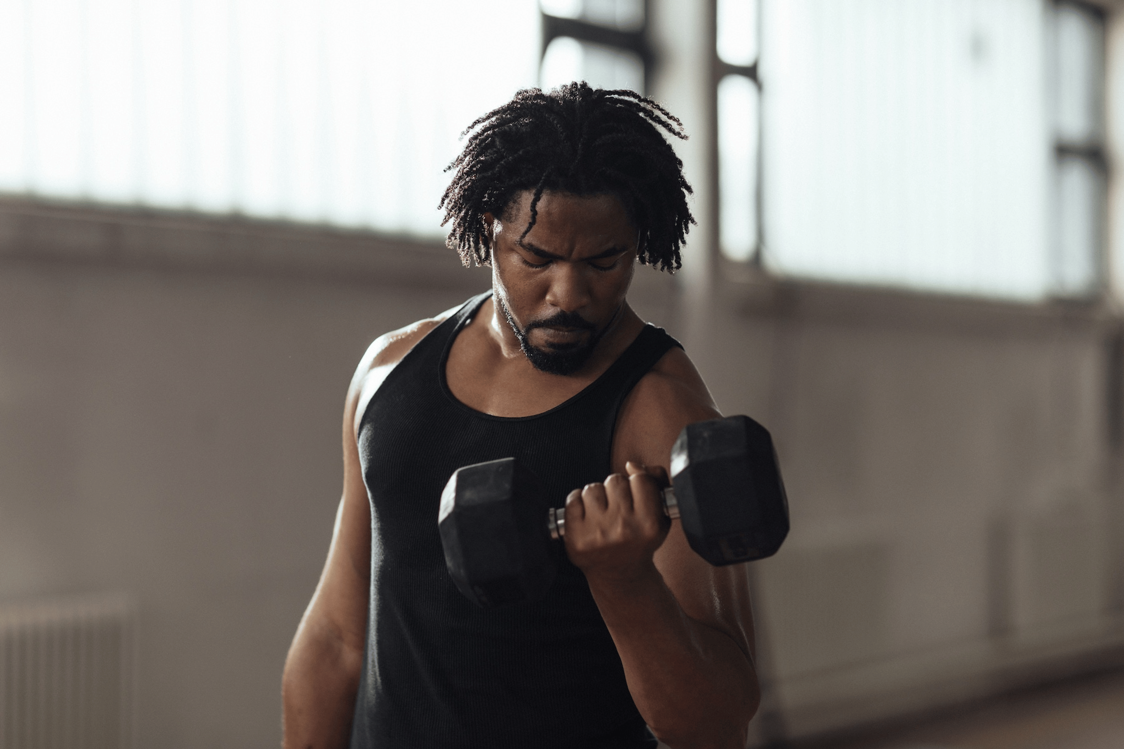 A man lifting dumbbells in a modern gym to build muscle.