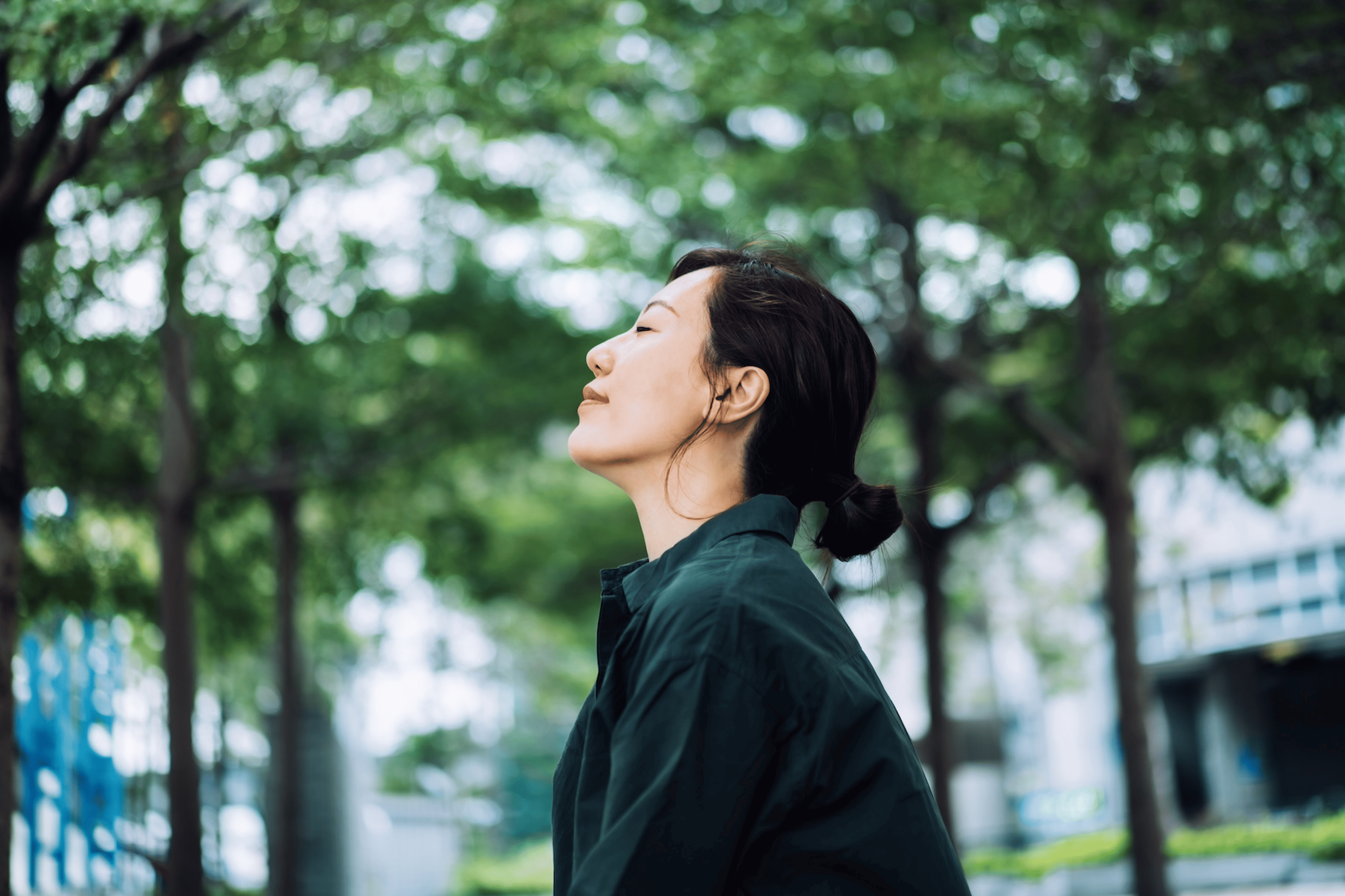 A woman closing her eyes as she sits outside and practices visualization meditation.