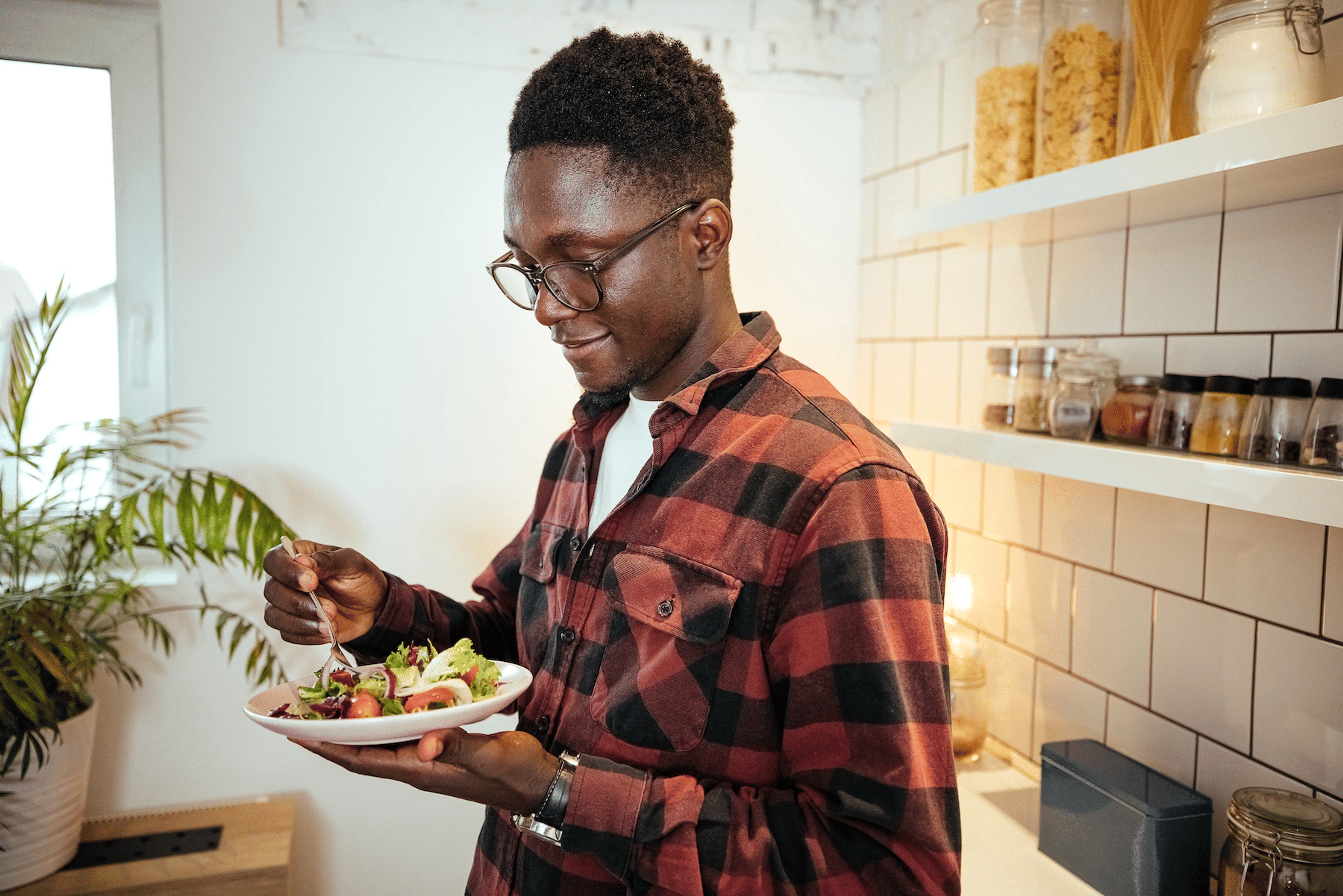 A man eating a veggie-filled salad, which is a good source of complex carbohydrates.