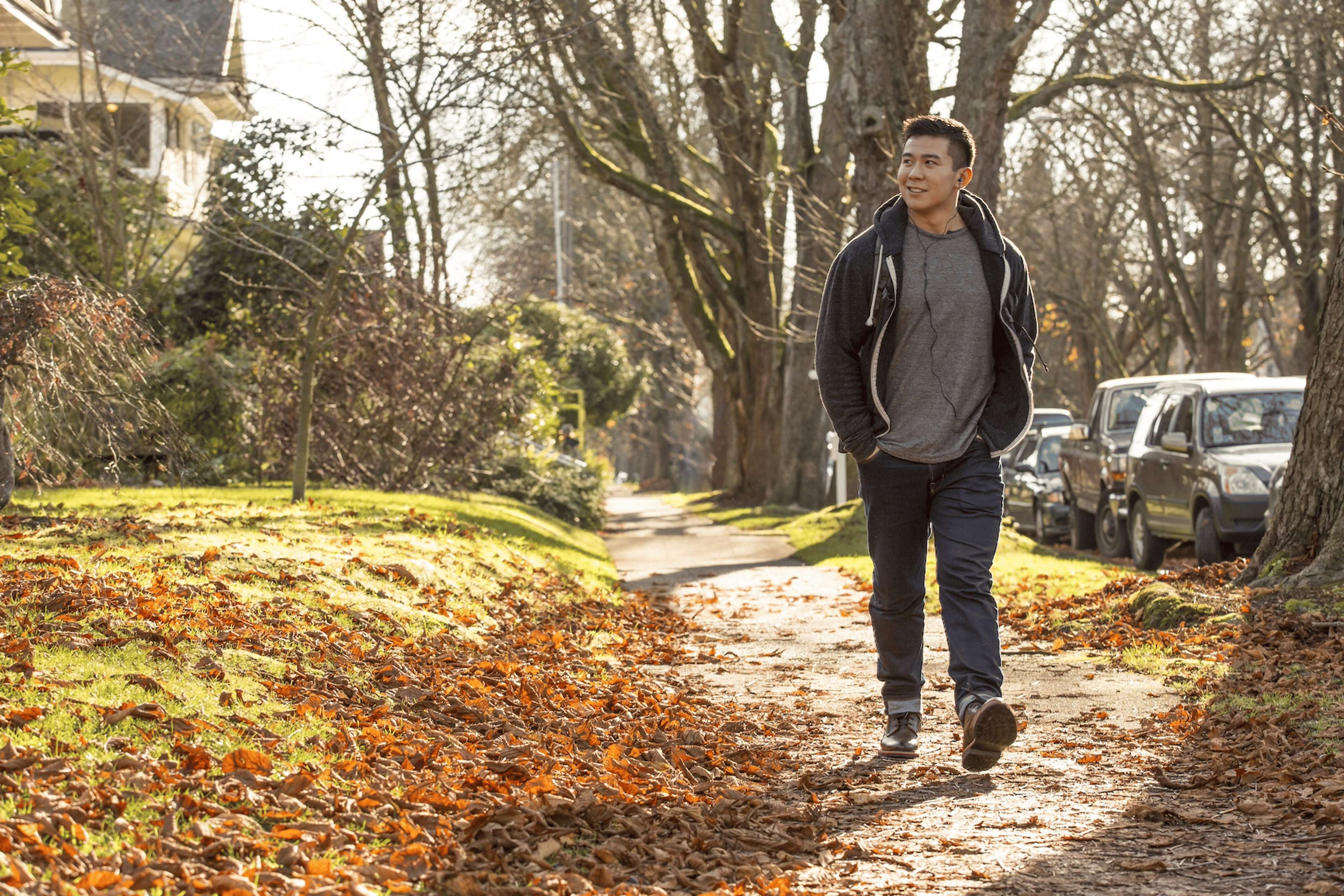 A man walking after eating. He is strolling through a suburban neighborhood in a fall setting.