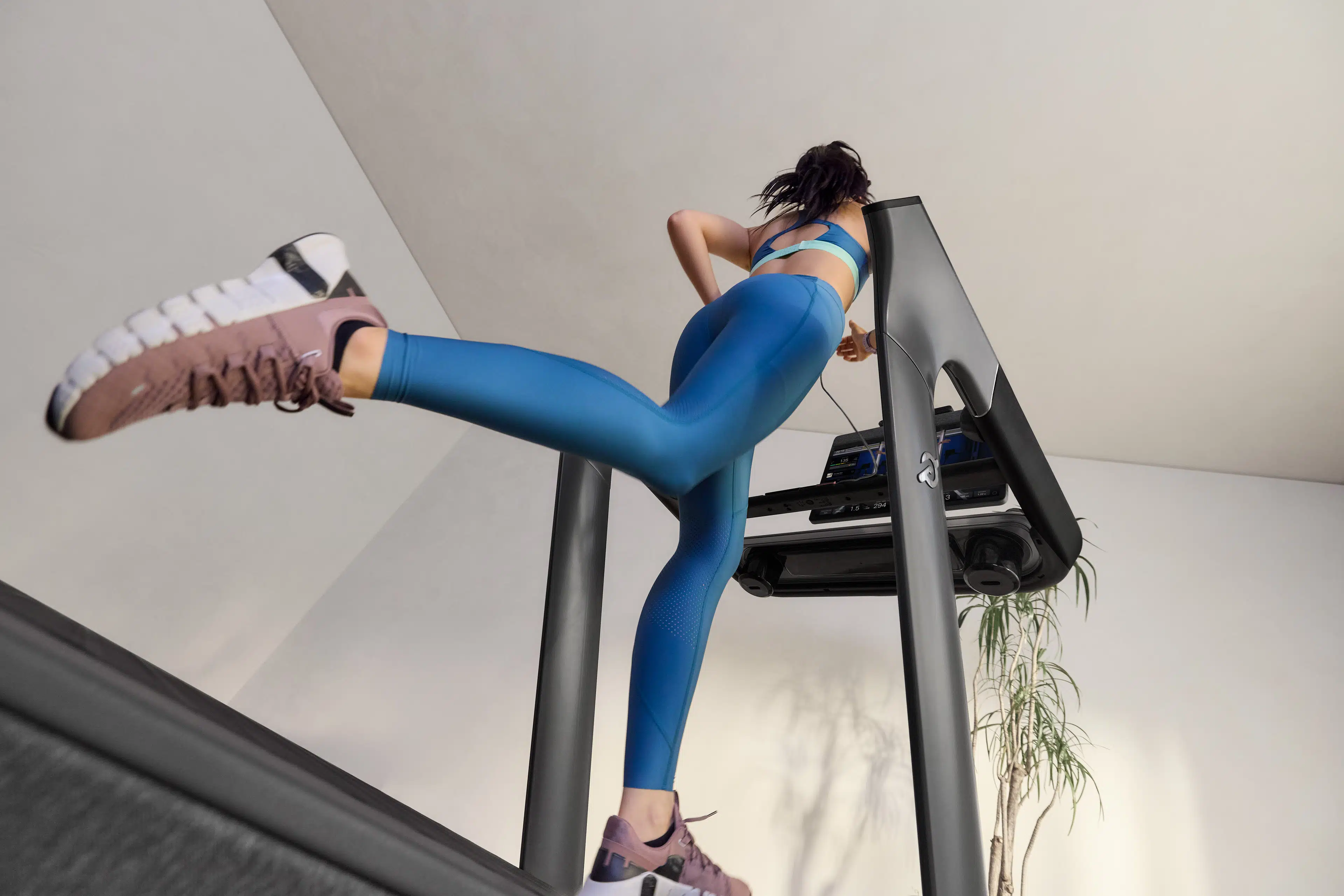Woman inside running on a Peloton Cross Training Series treadmill while transitioning her outdoor runs to inside.