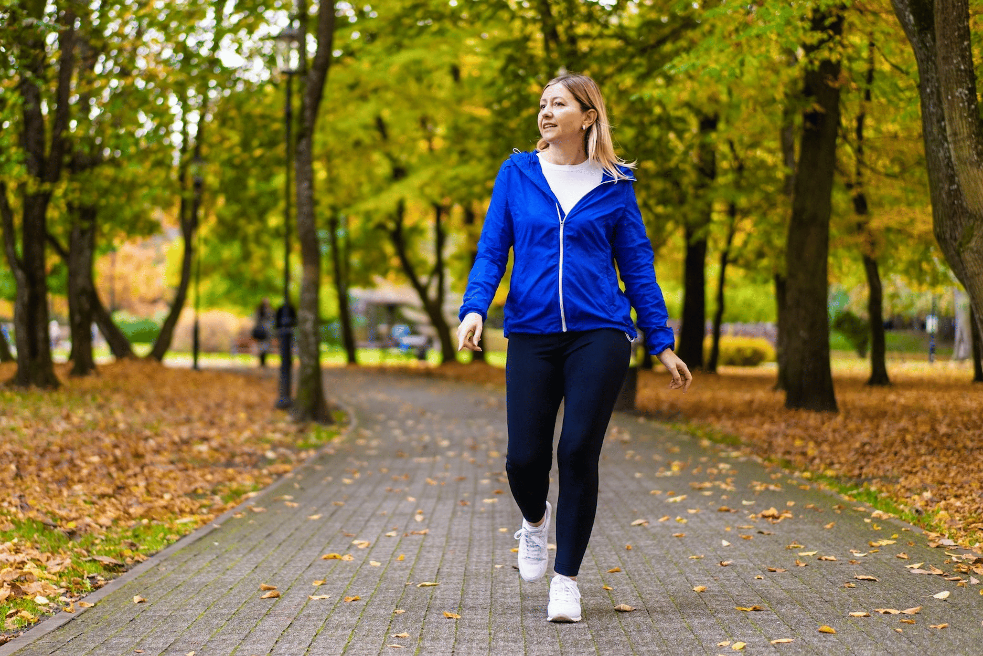 A woman walking after eating. She's going for an outdoor walk in a local park.