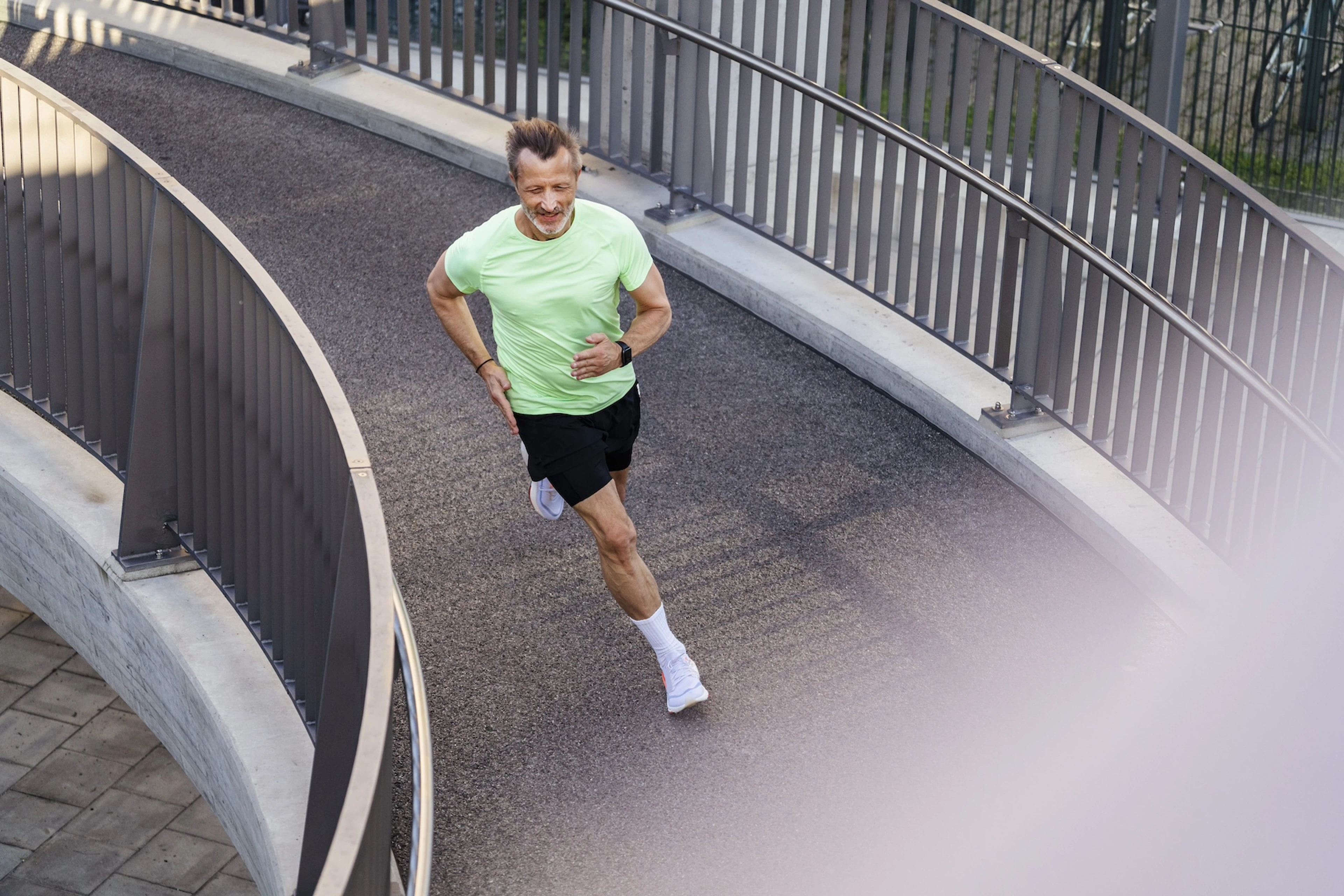 A man running outside on a footbridge. 