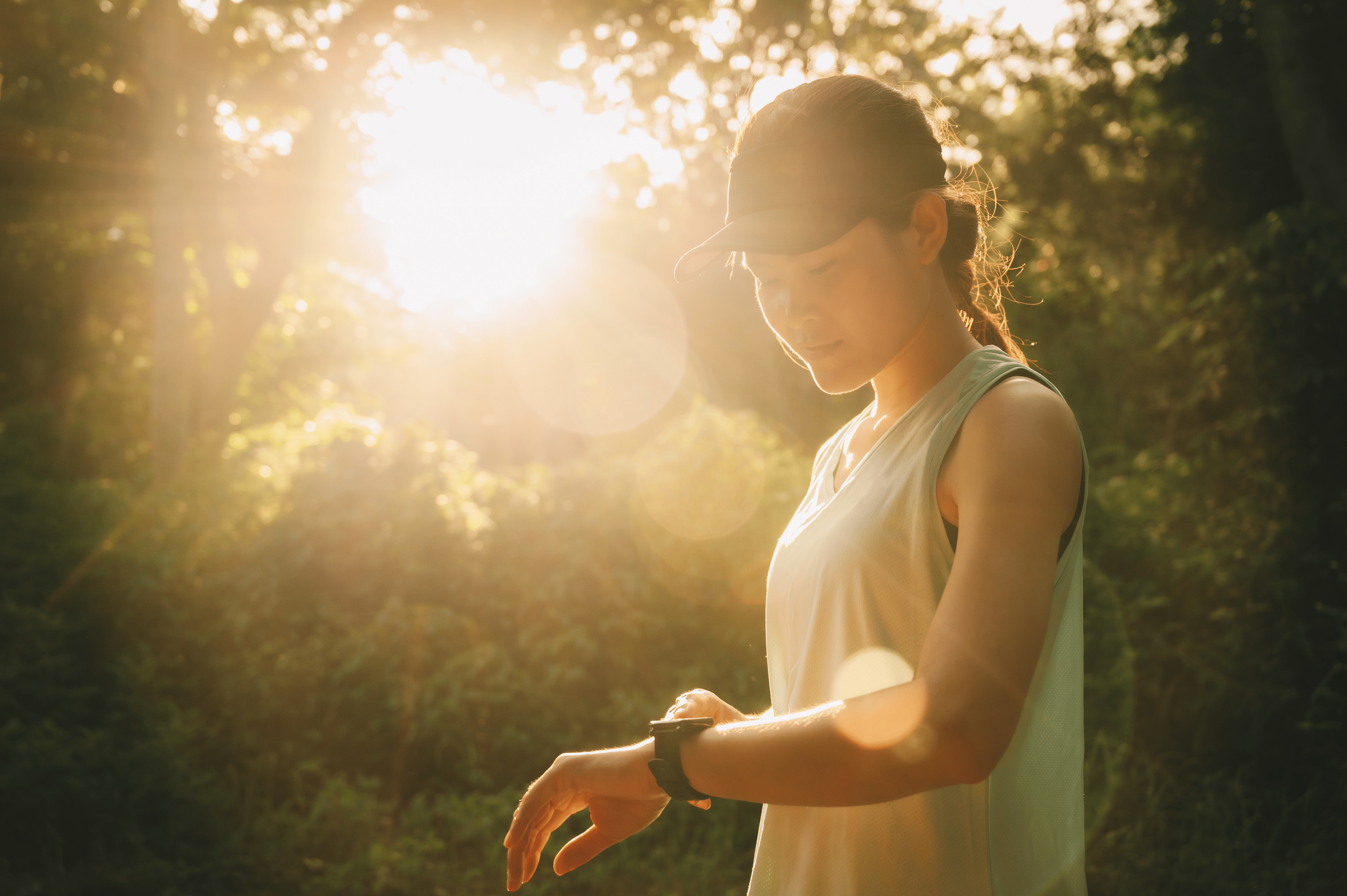Woman looking at her smartwatch in a park while running in the morning 