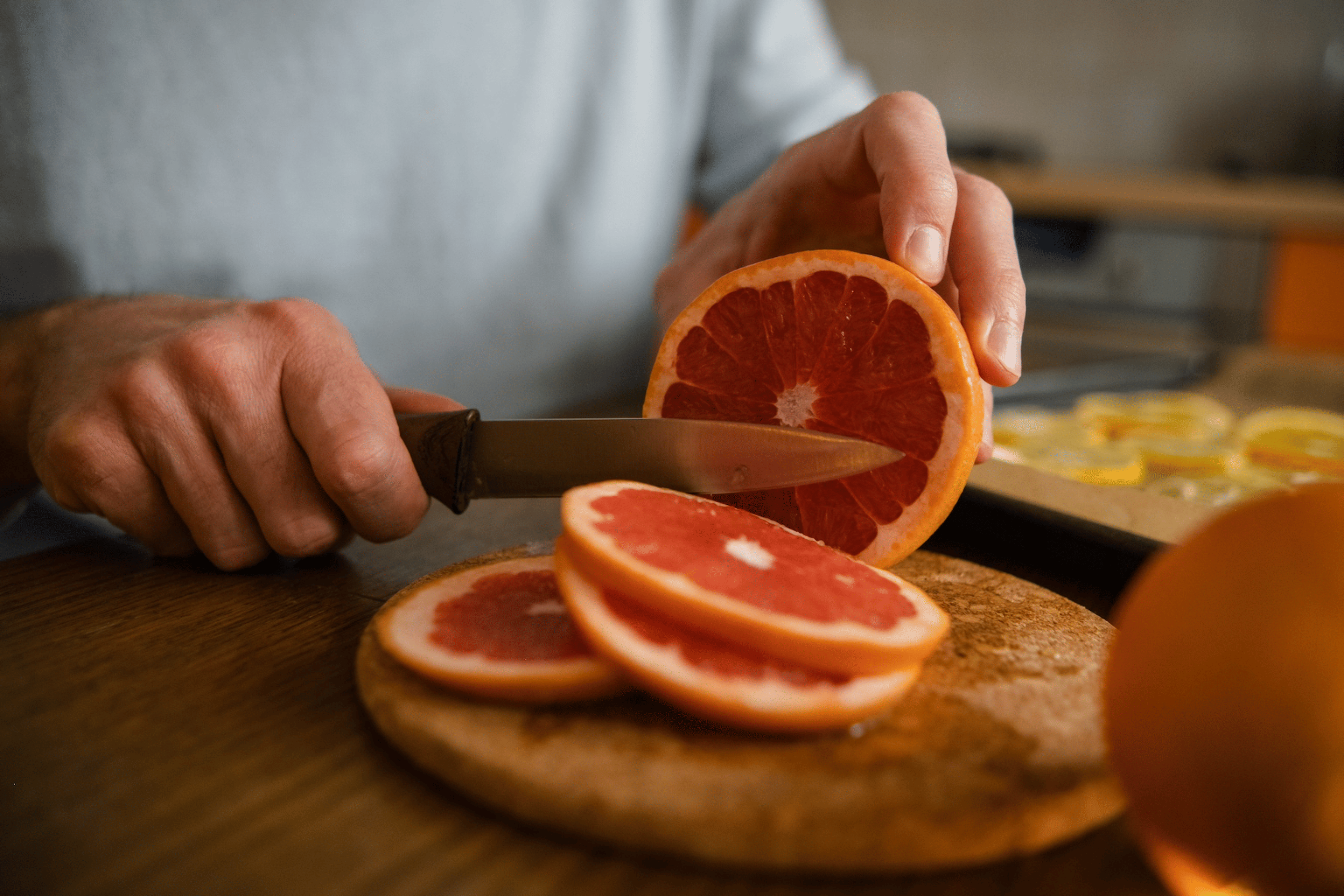 A man cutting a grapefruit, a hydrating food, into slices.