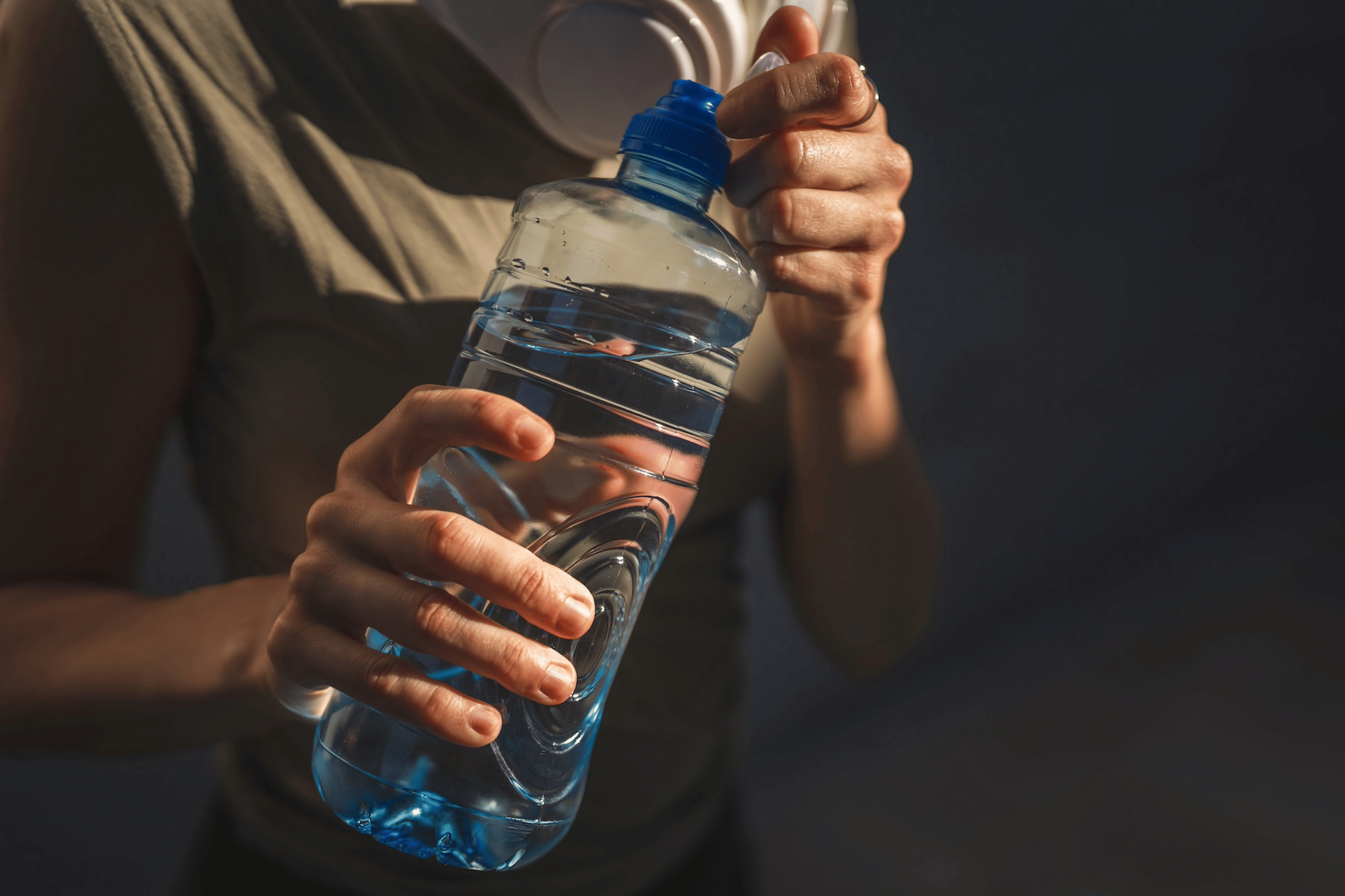 A close-up photo of an athlete holding a clear water bottle to stay hydrated as part of their cycling nutrition strategy.