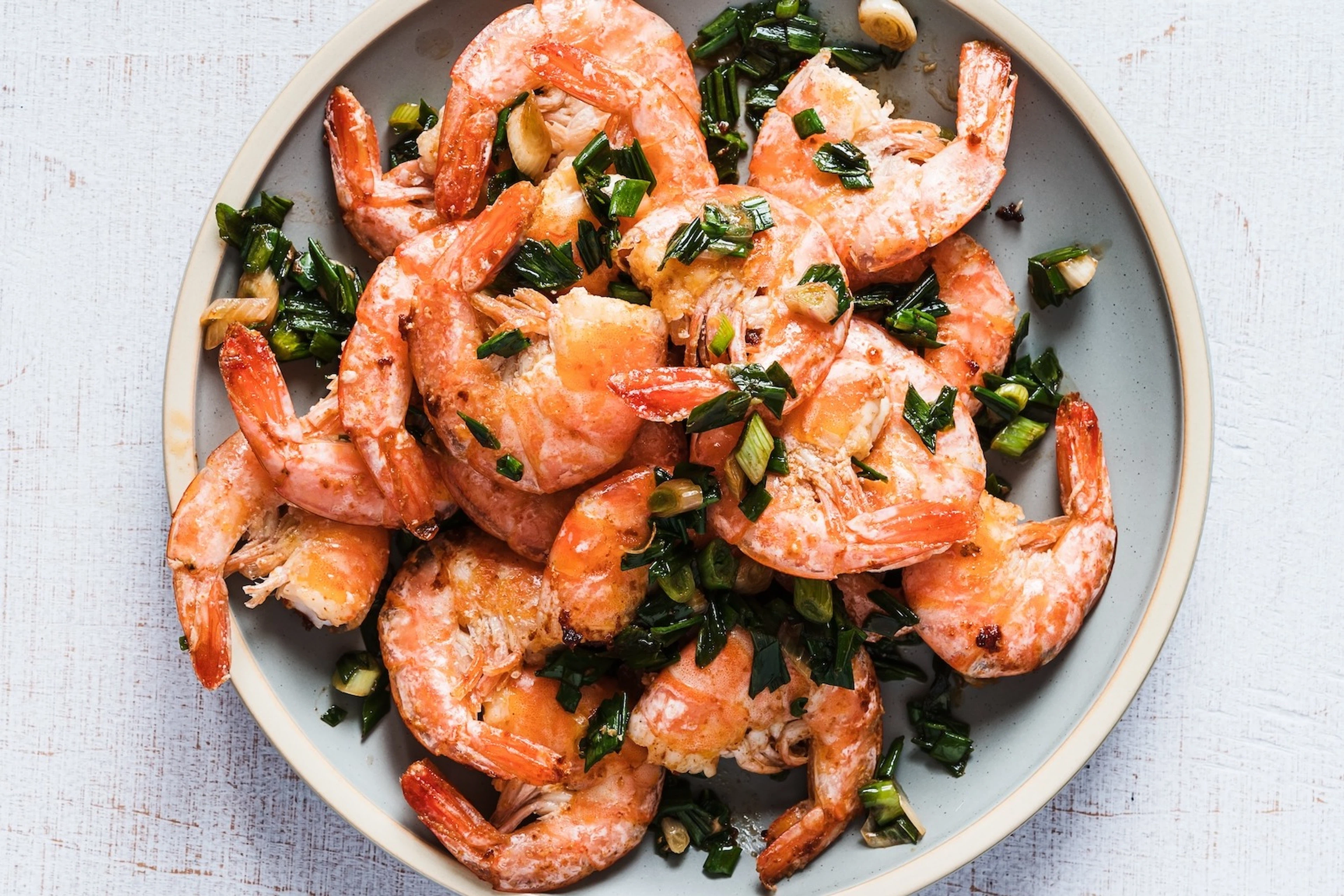 A plate of shrimp with scallions.