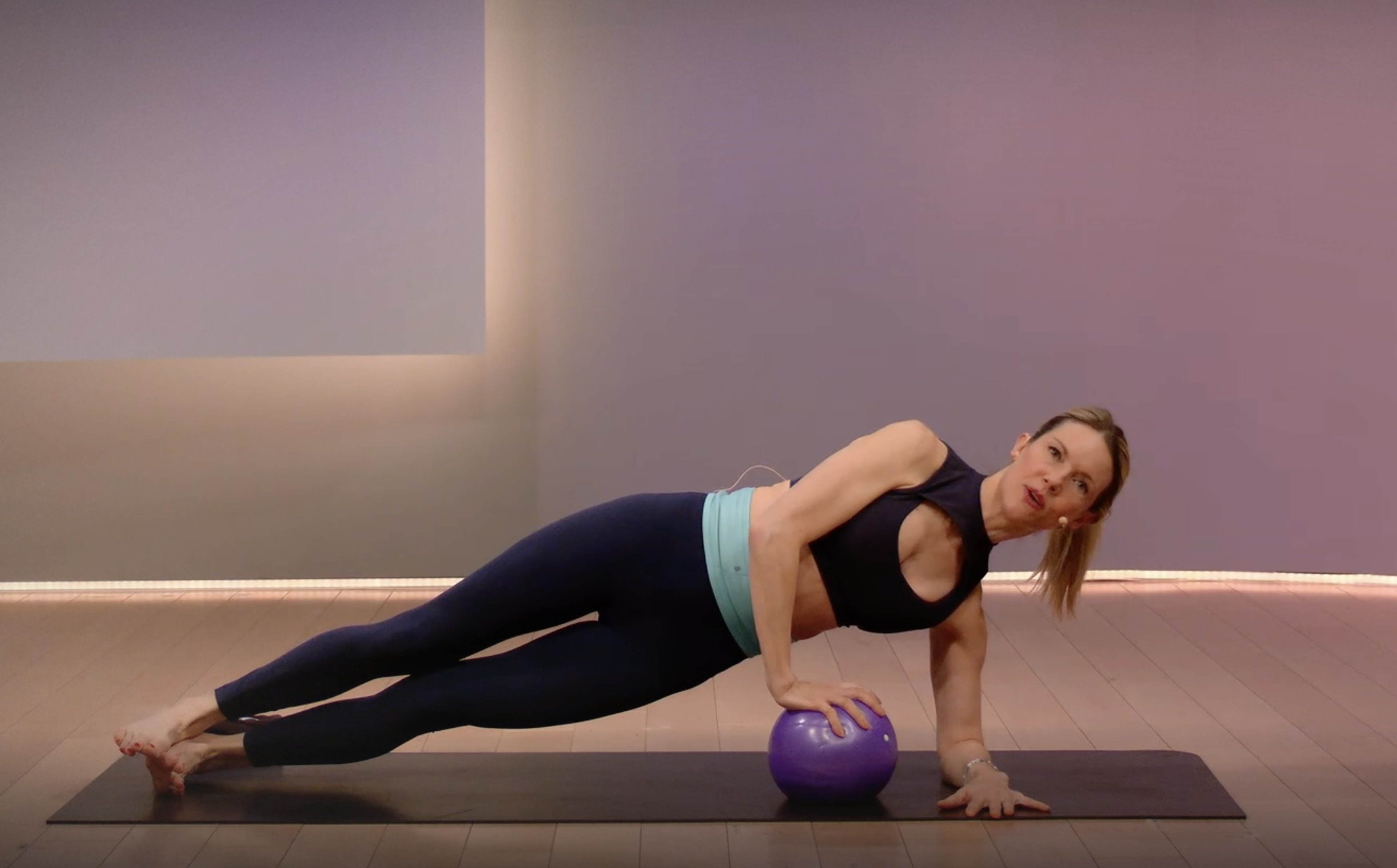 Kristin McGee demonstrates a side plank exercise with a Pilates ball 