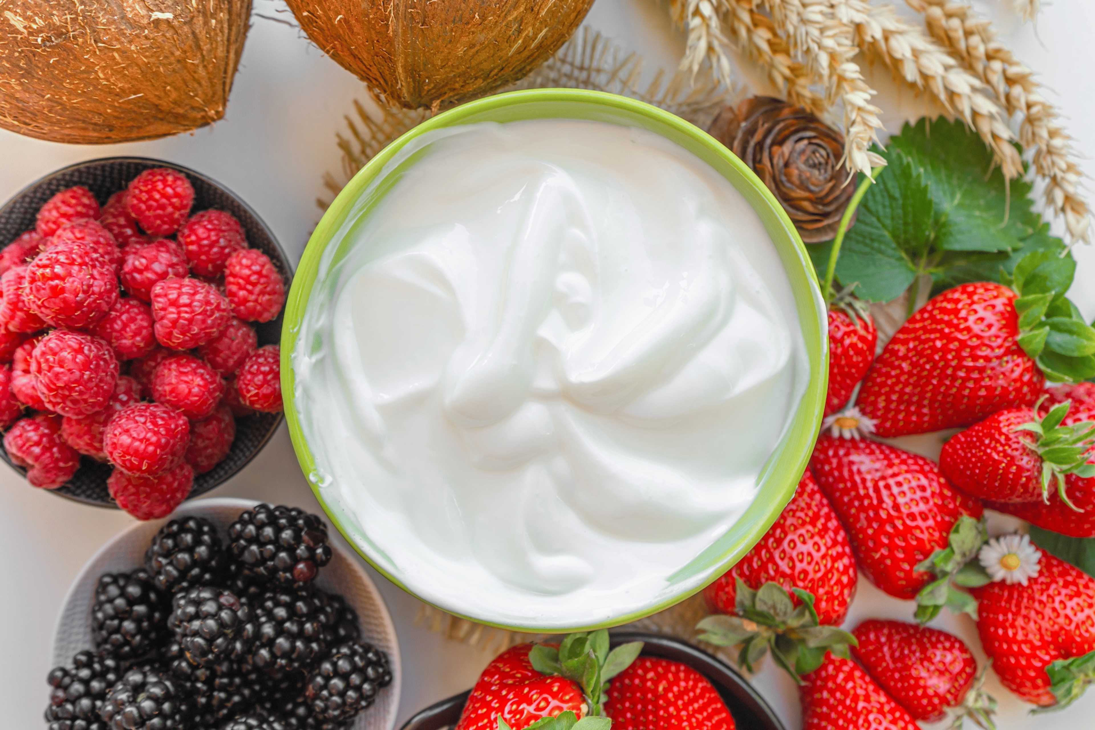 A bowl of Greek yogurt surrounded by bowls of berries. 