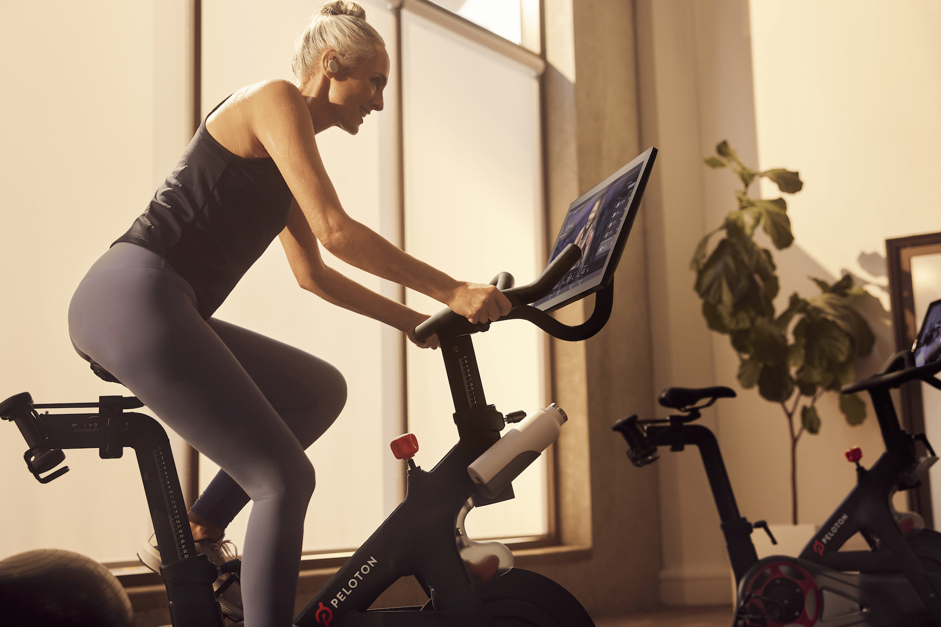 Woman cycles at home on Peloton Bike.