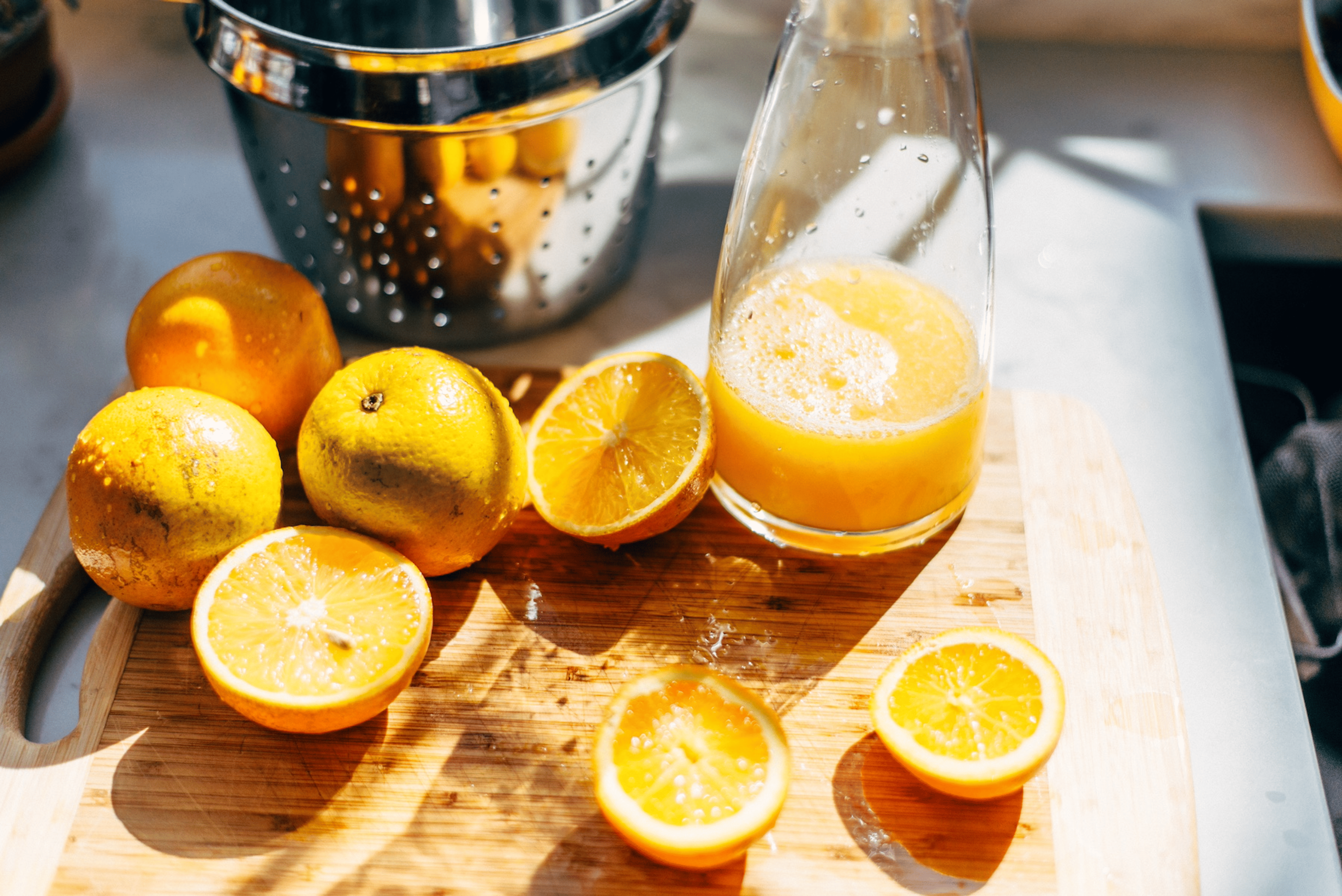 A carafe of freshly squeezed 100 percent orange juice, a hydrating food, next to a cutting board of sliced oranges.