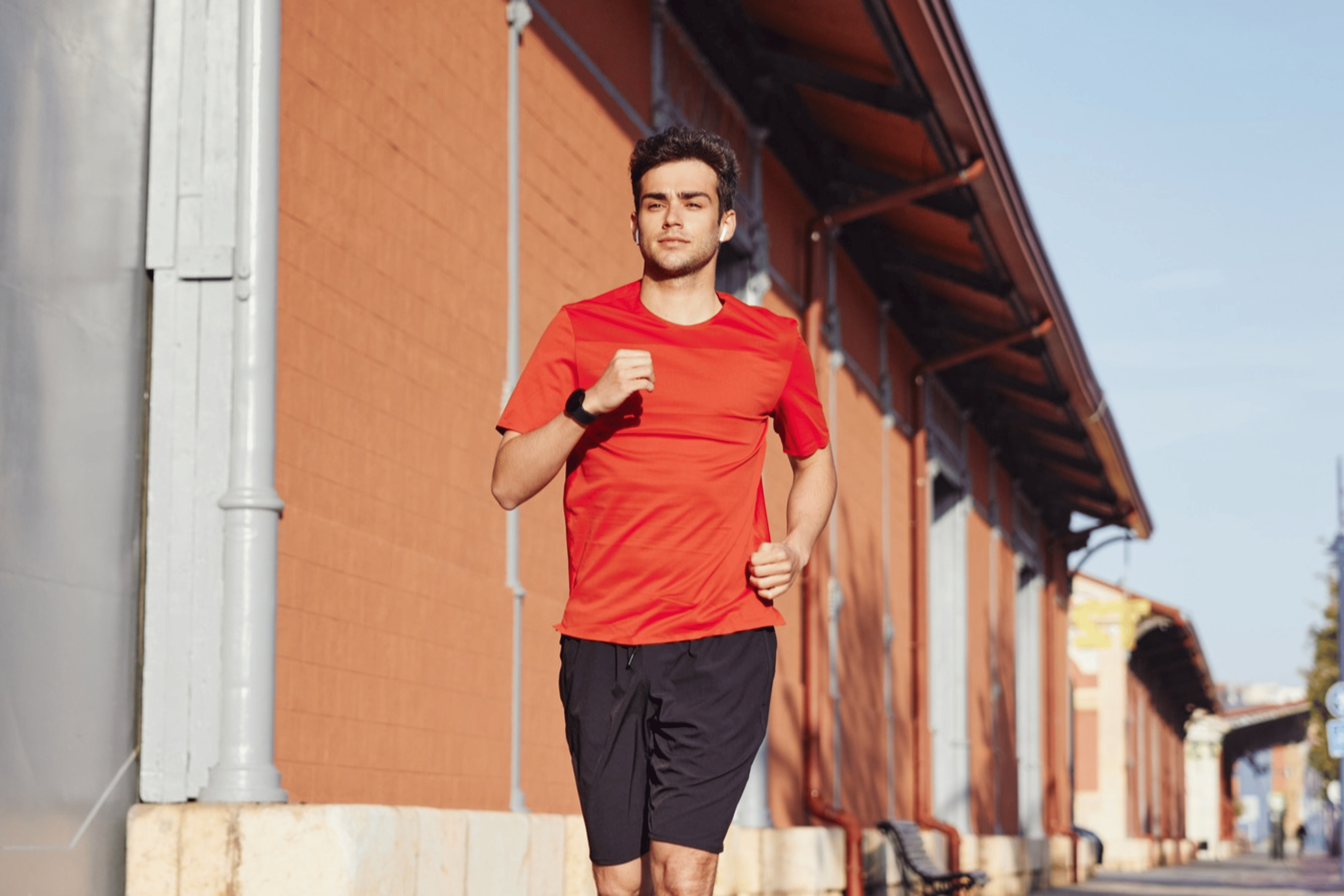 Man wearing red shirt running down street