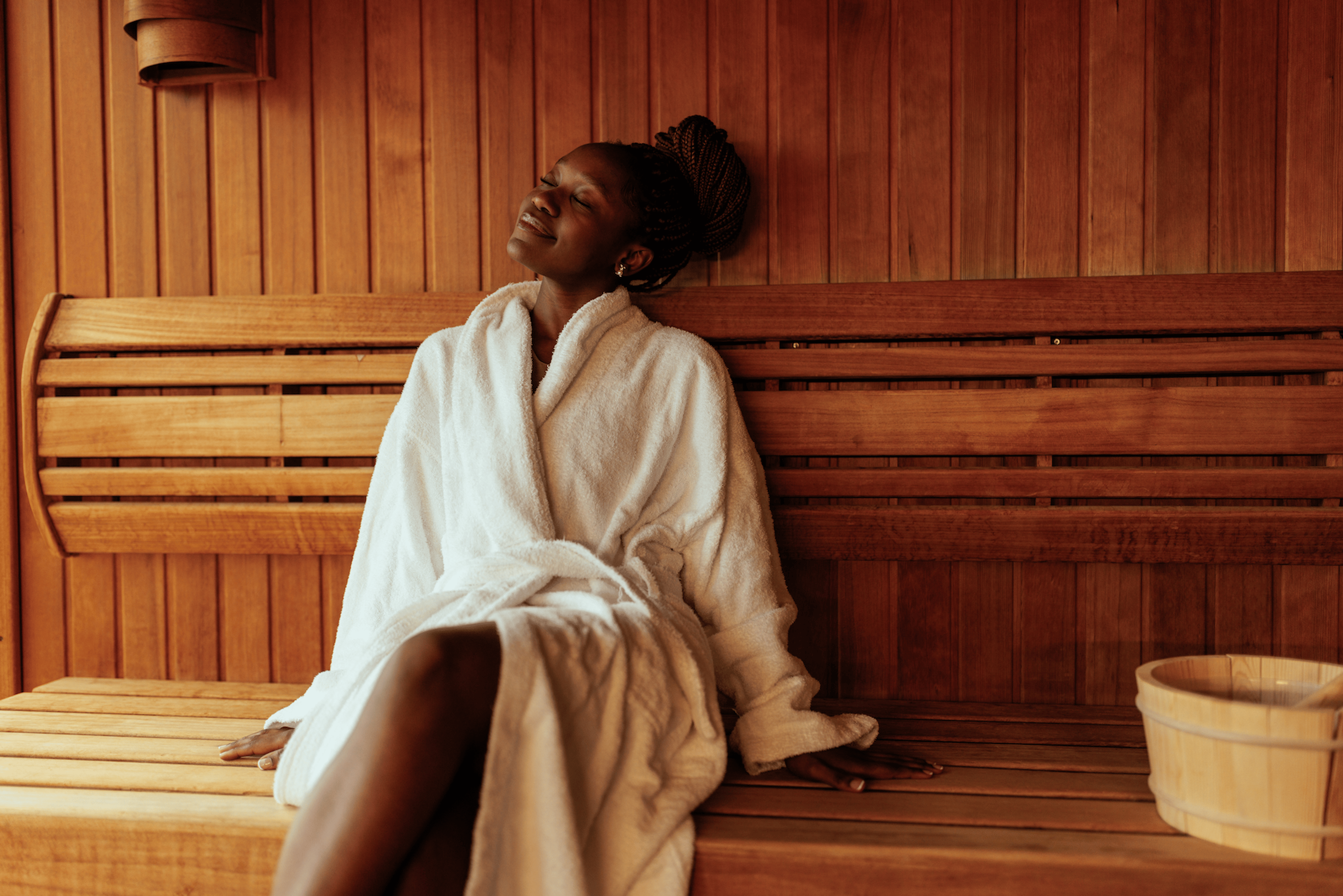Wellness Trends: A woman in a white robe relaxing in a sauna.