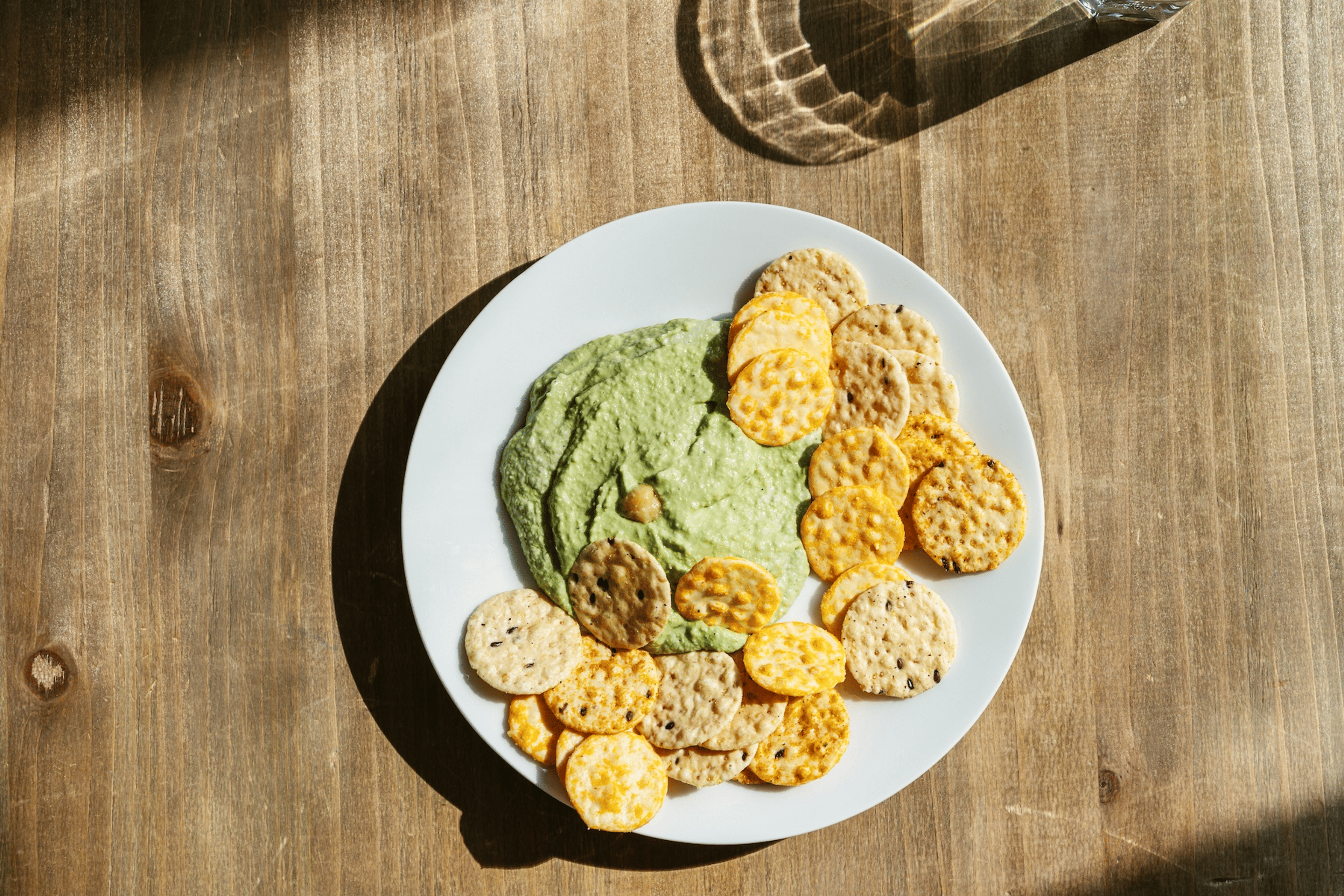 A plate of crackers and hummus sitting on a table.