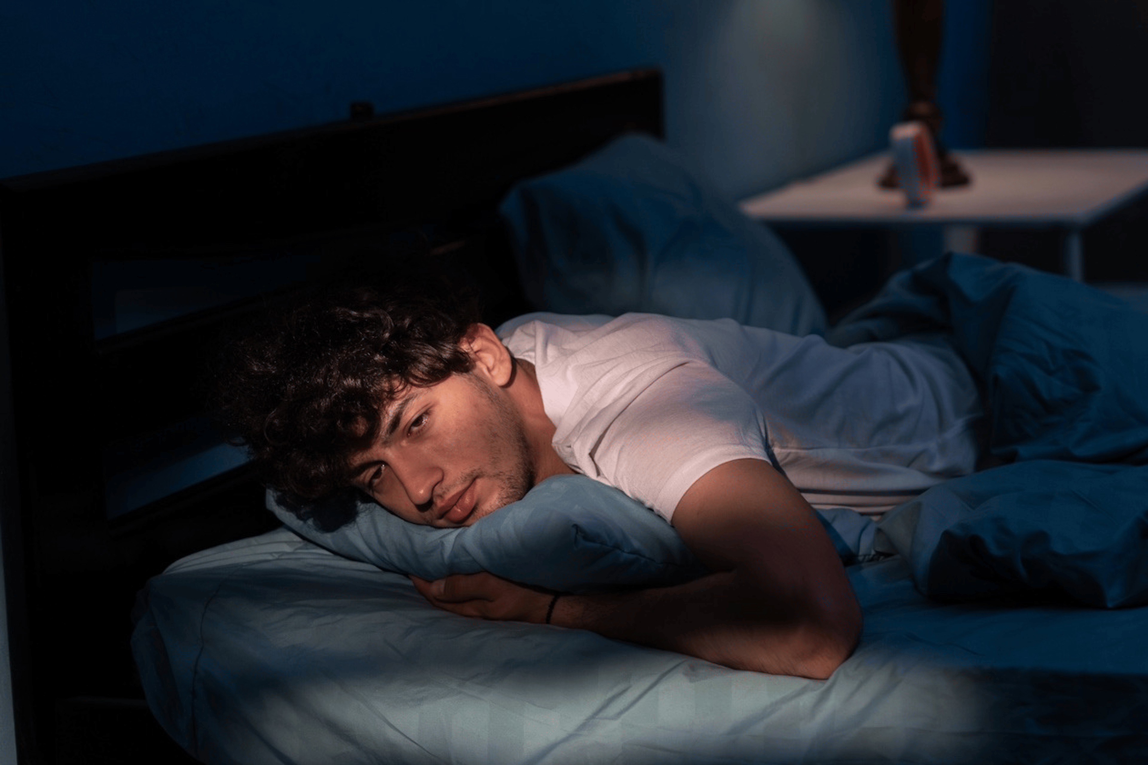 A man lying awake in his bed. He can't sleep after exercising.