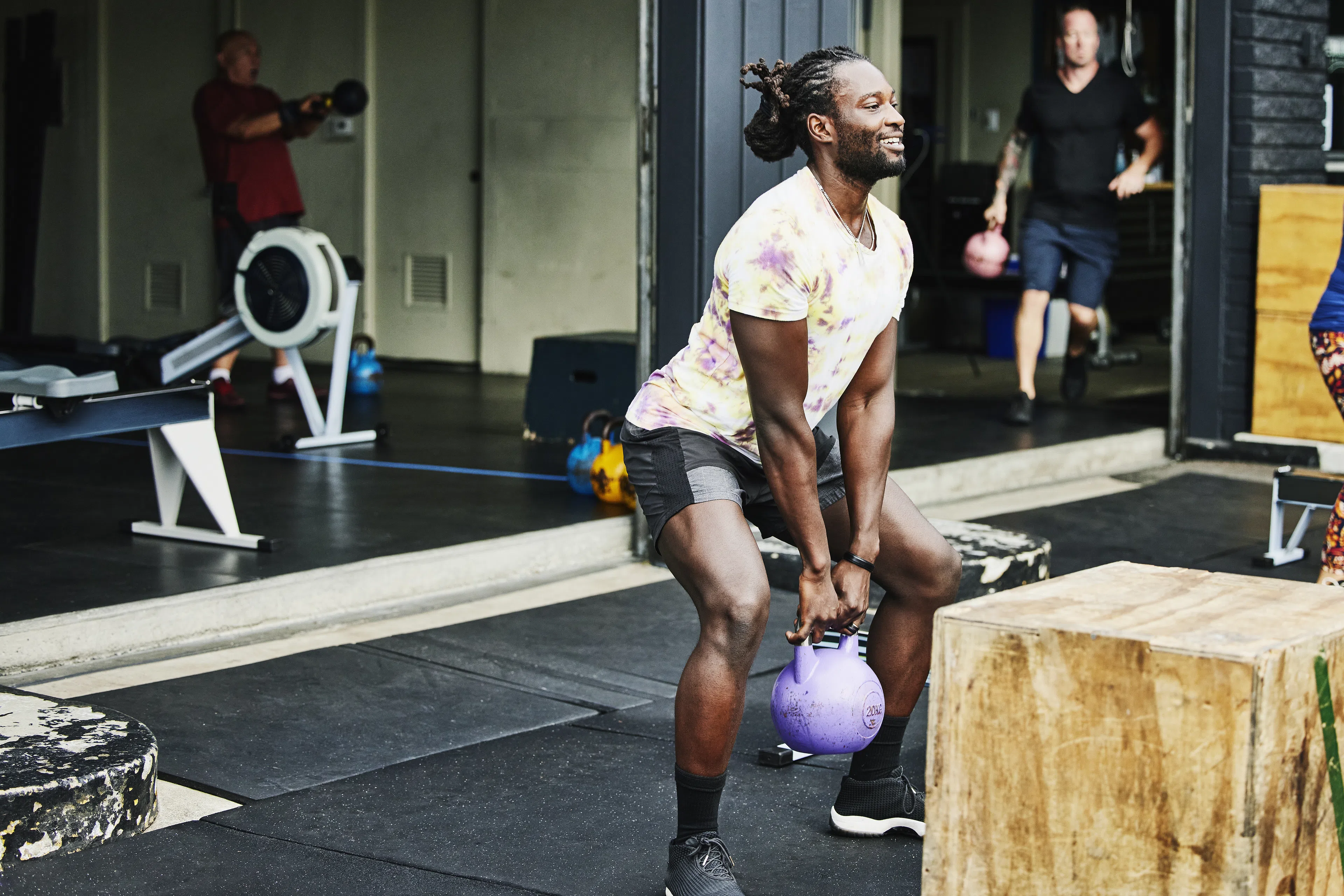 Man in a gym doing kettlebell squats with a 20lb purple kettlebell