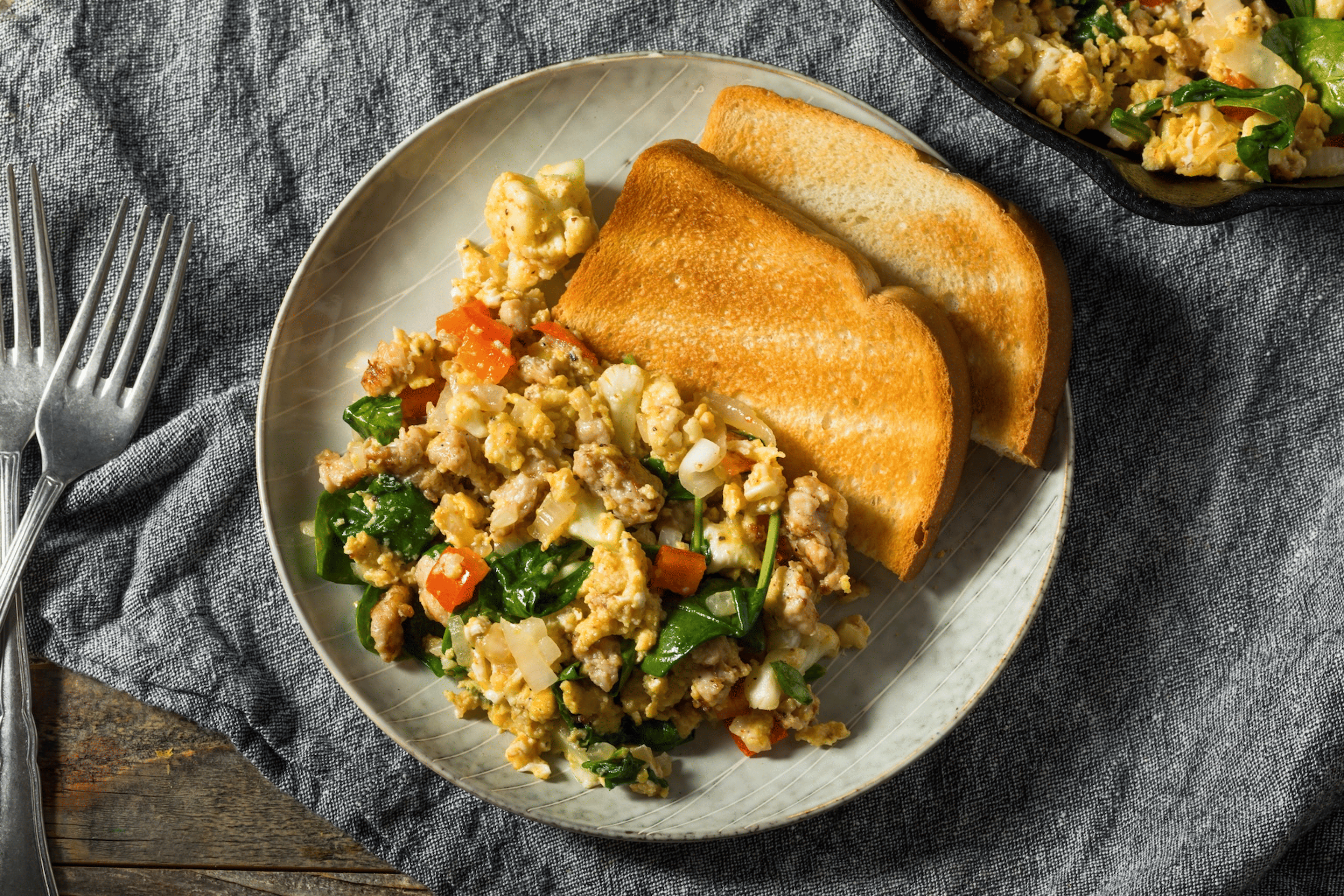 A healthy breakfast option of scrambled eggs with veggies mixed in and some whole-wheat toast on the side.