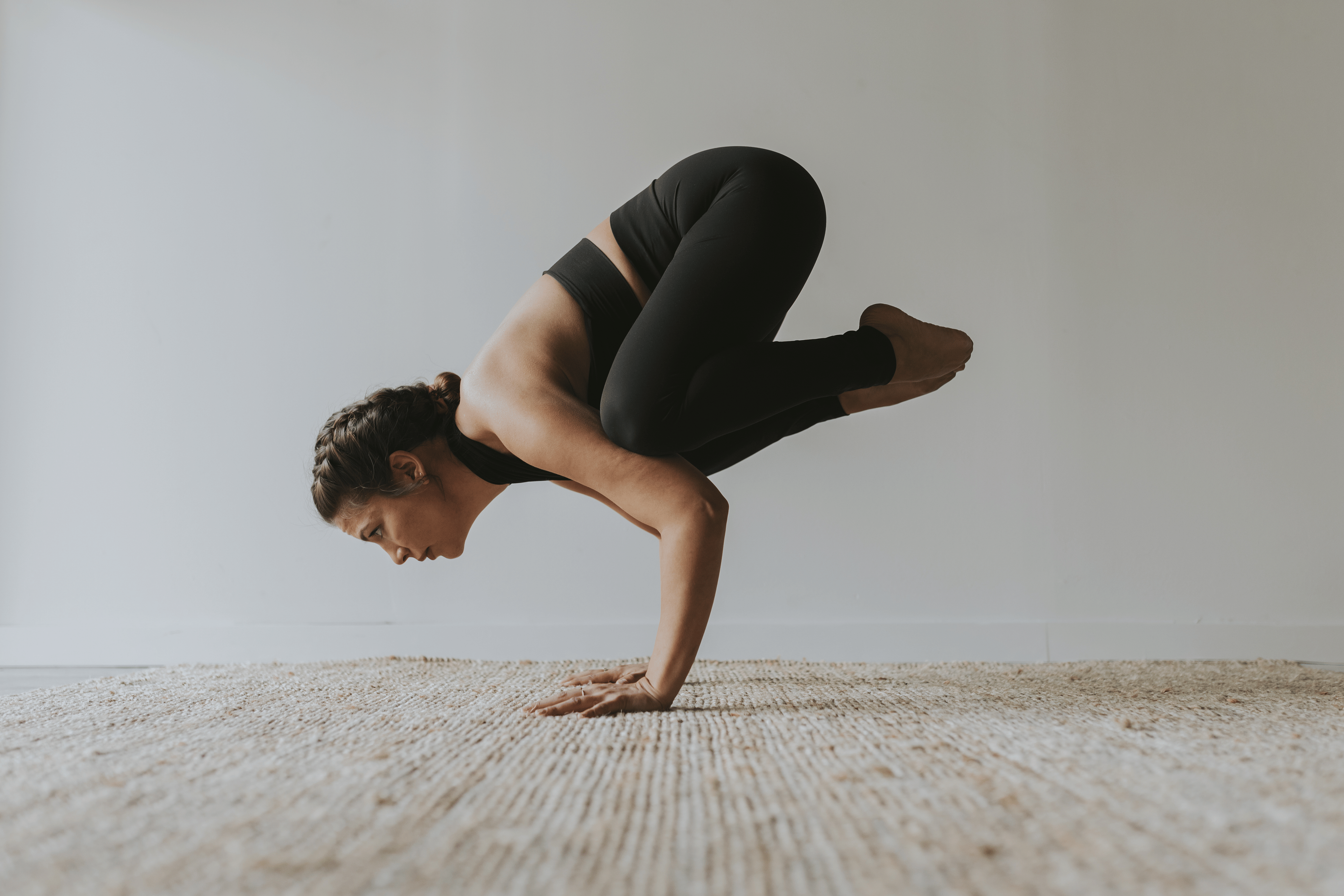 Woman practices Crow Pose, and advanced yoga pose
