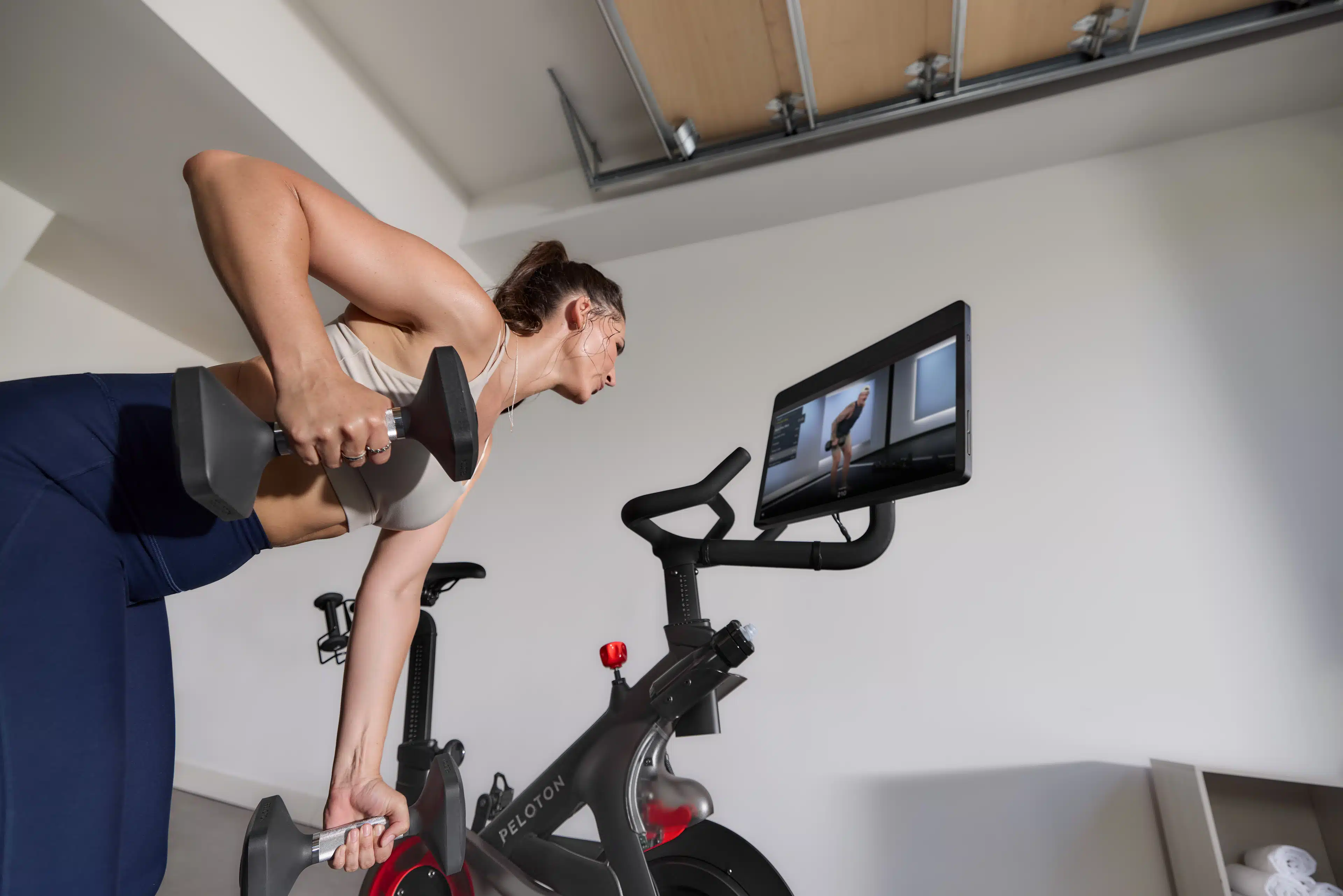 Woman doing a strength workout and taking advantage of all the strength training features on the Peloton Cross Training Bike+ powered by Peloton IQ.