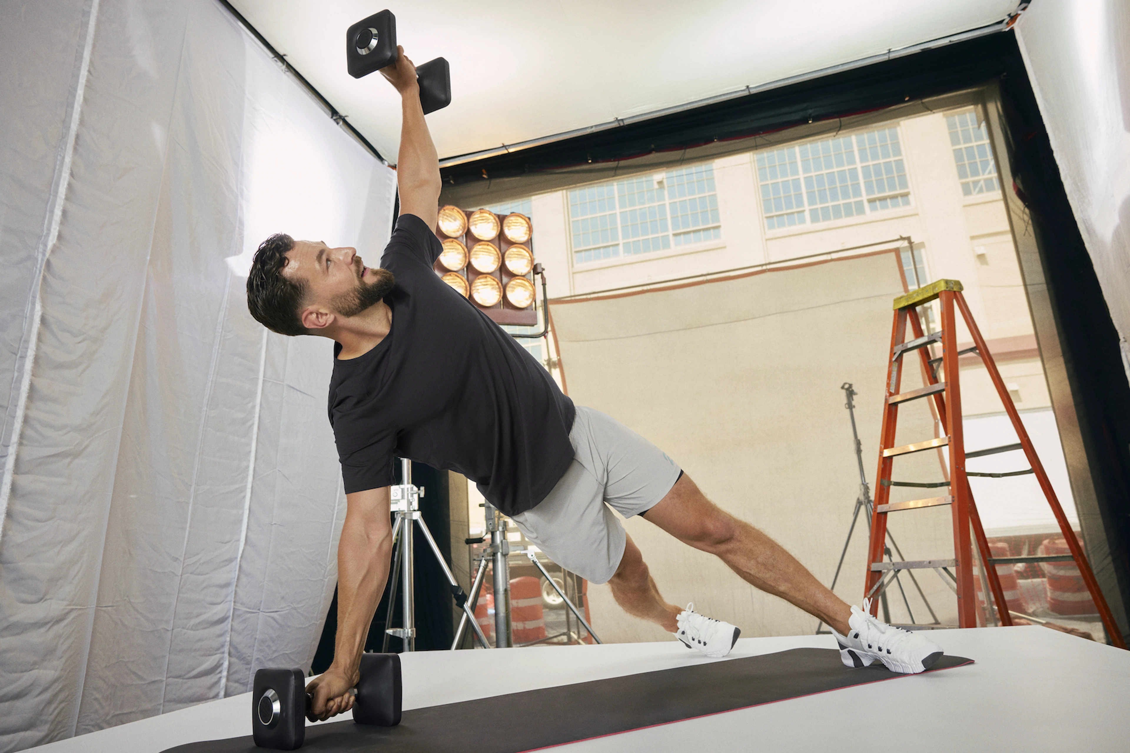 In this image for an article about how gym clothes affect motivation and performance, Peloton instructor Erik Jäger is doing a side plank with weights on a workout mat.