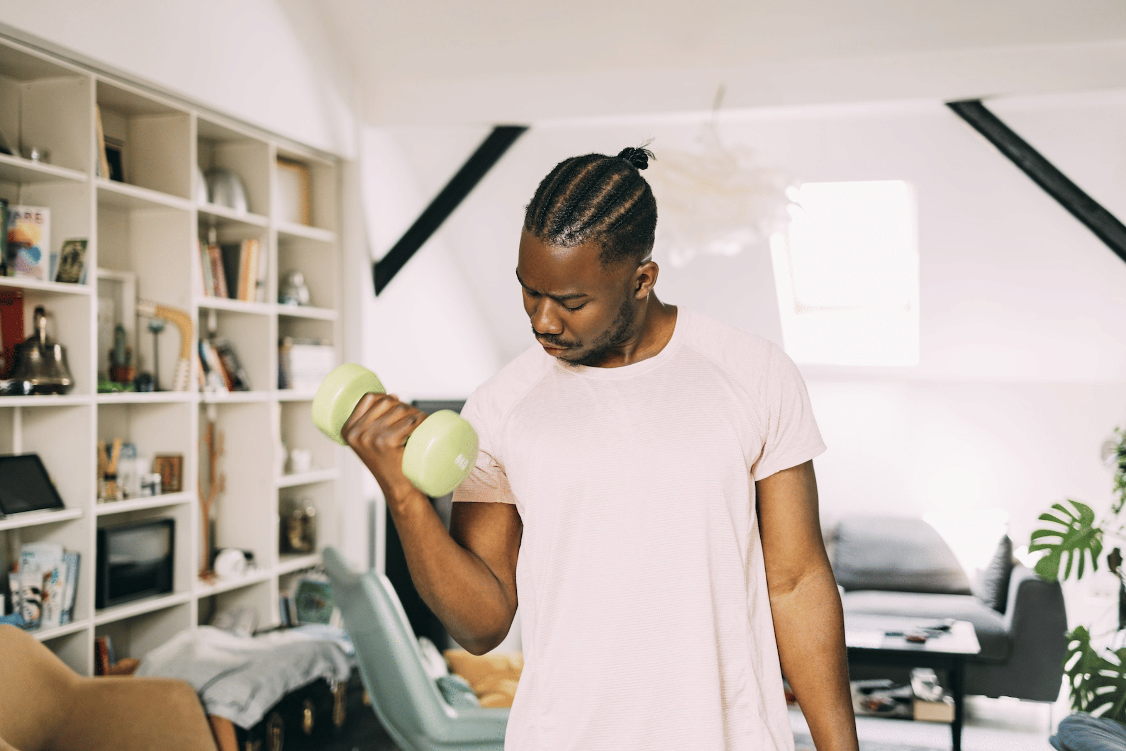 A man doing single-arm bicep curls with a dumbbell at home.