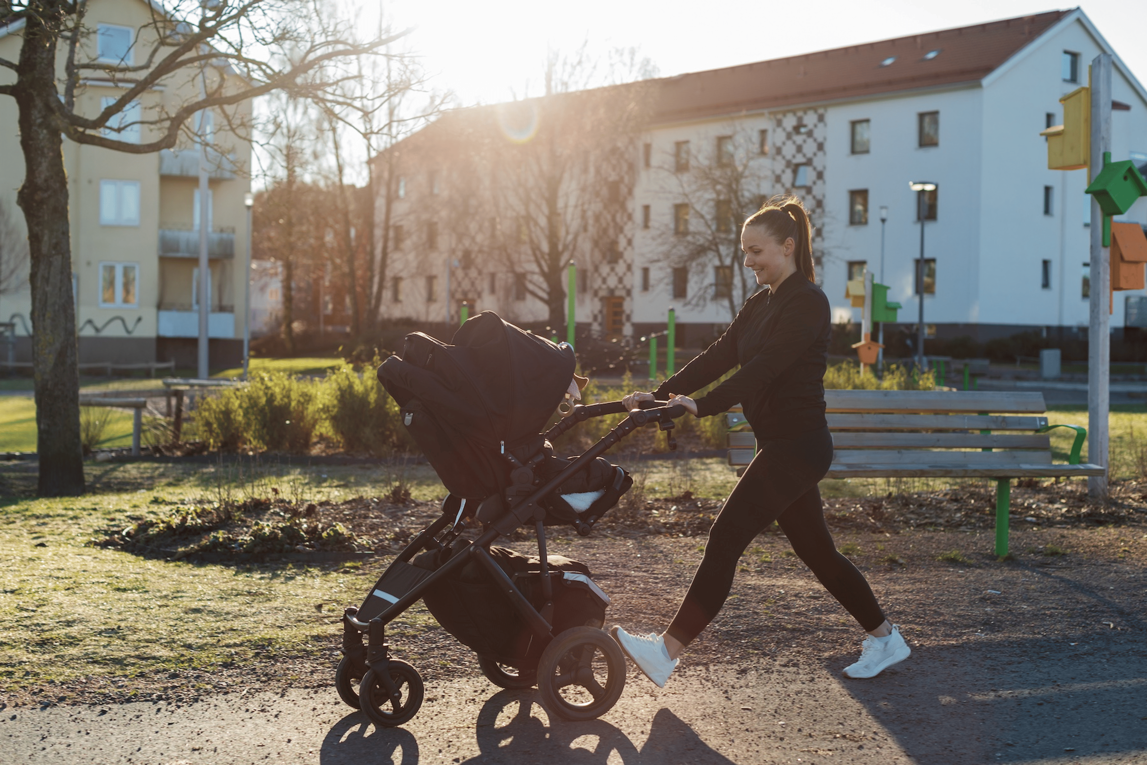 A new mom going for a walk outdoors with her baby in a stroller.