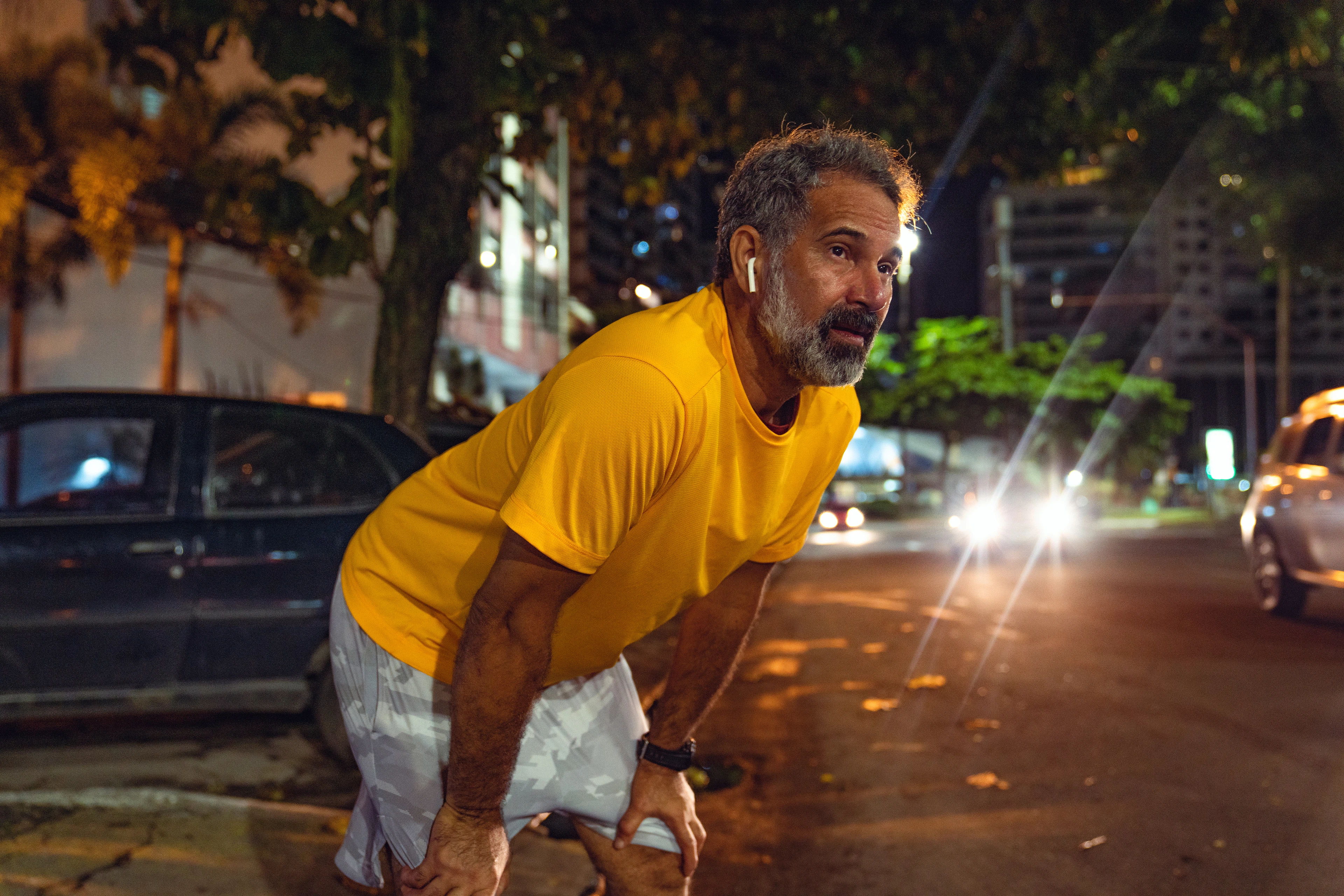 Man taking a break while running at night during a training plan where he's running twice a day.