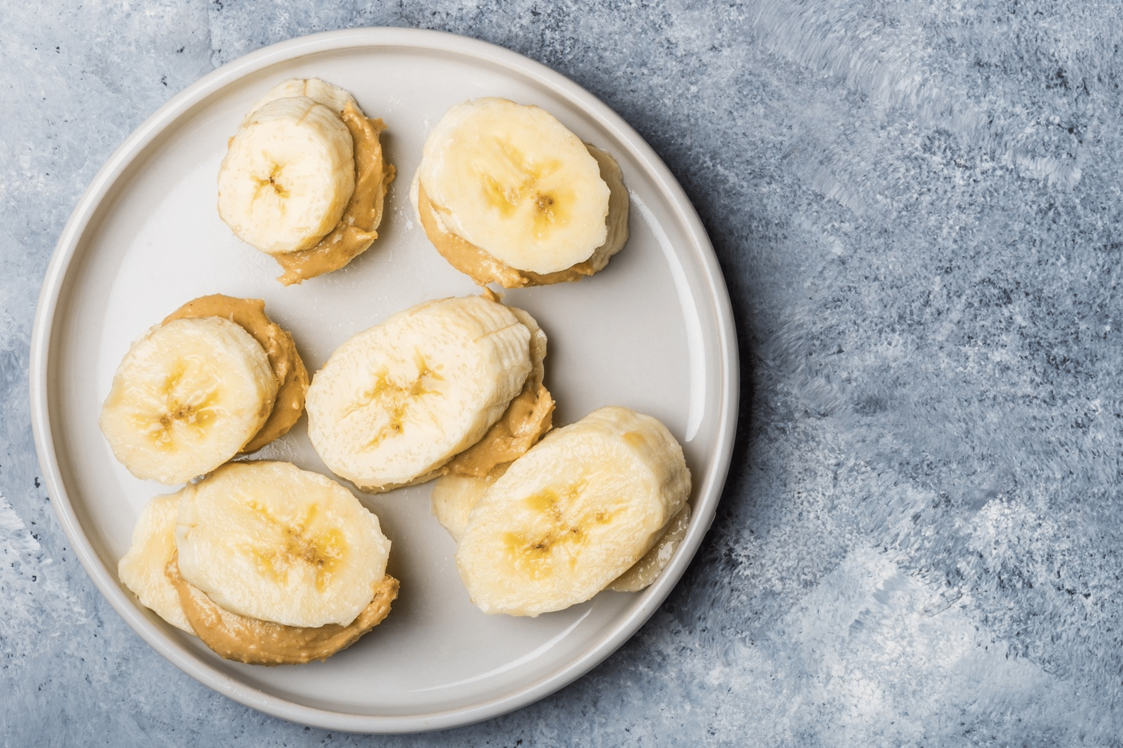 A plate of banana slices and peanut butter, which is a high-protein snack.
