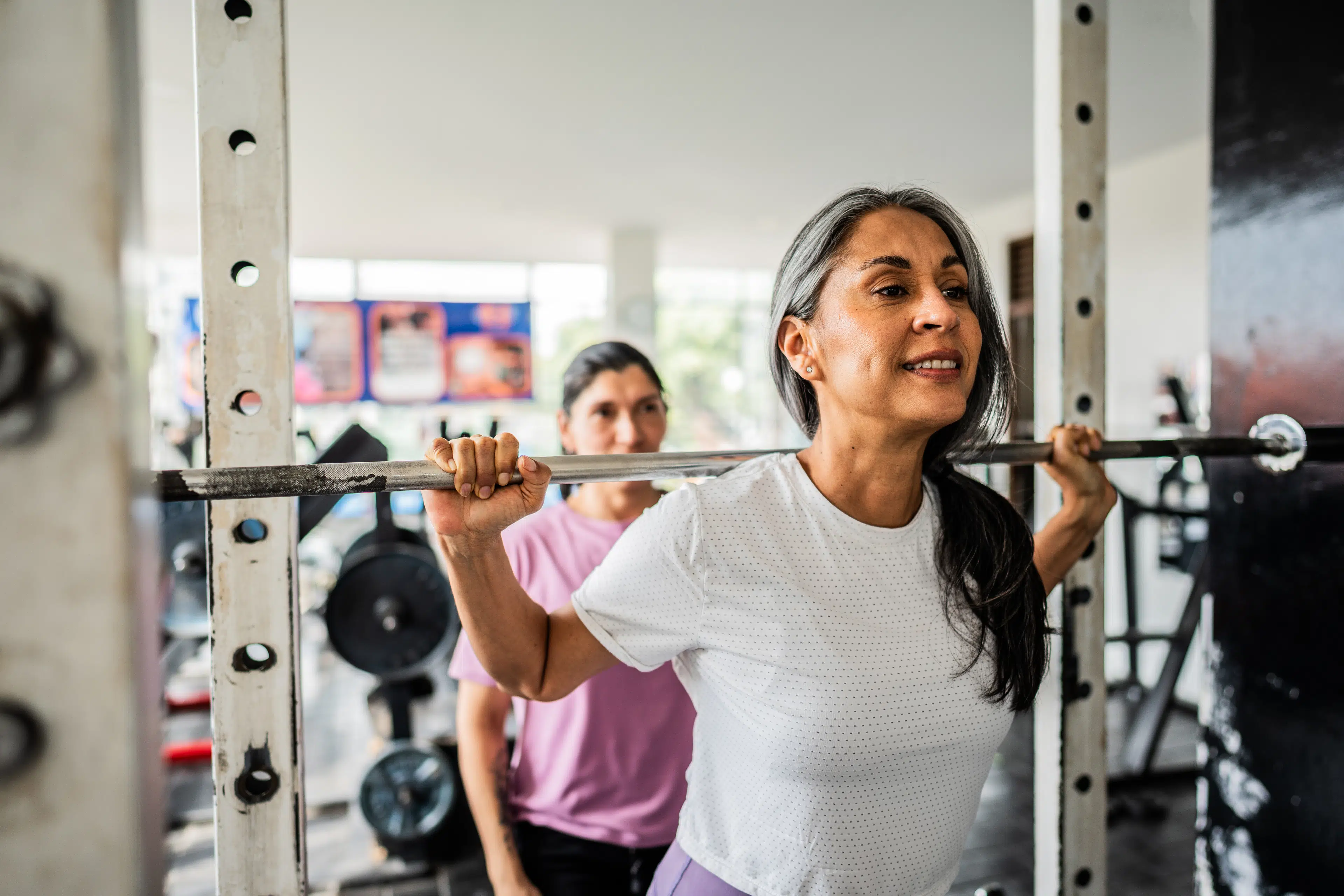 Woman squatting a barbell to build strength while exercising during menopause.
