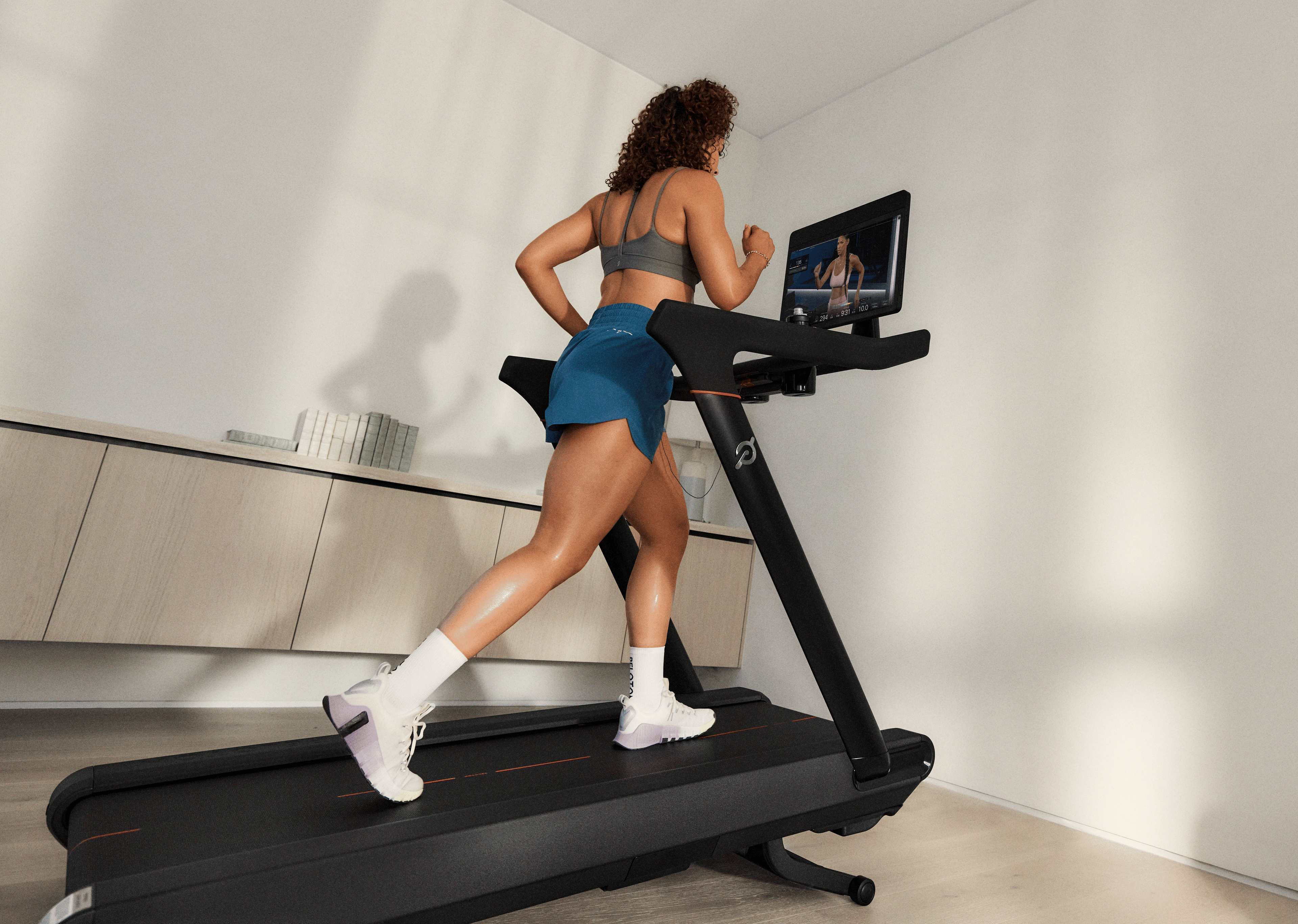 Woman doing a HILIT workout on her Peloton Cross Training Tread.