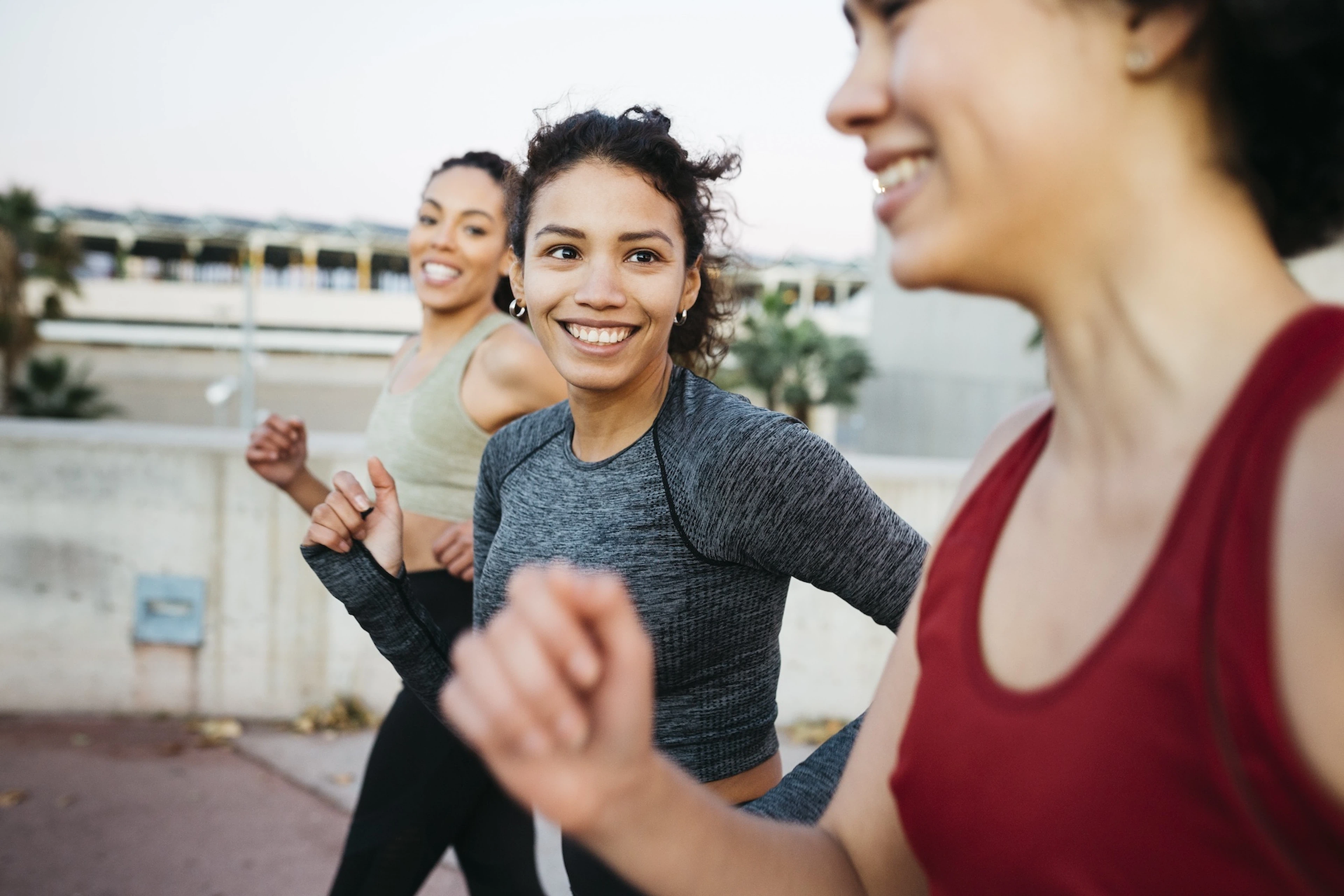 A group of three women practicing social wellness by going on a power walk outside together.