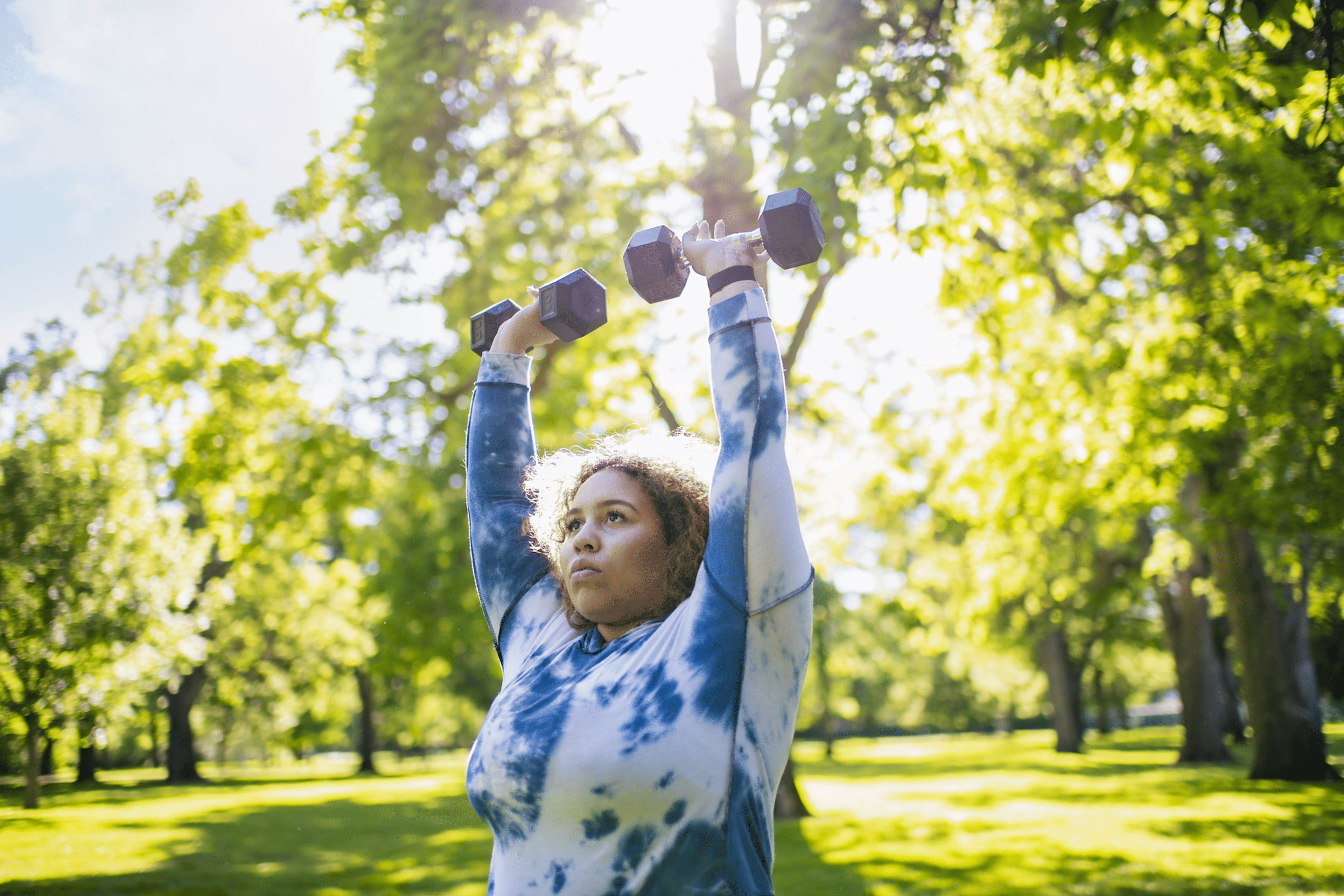 Woman does dumbbell shoulder exercises outside 